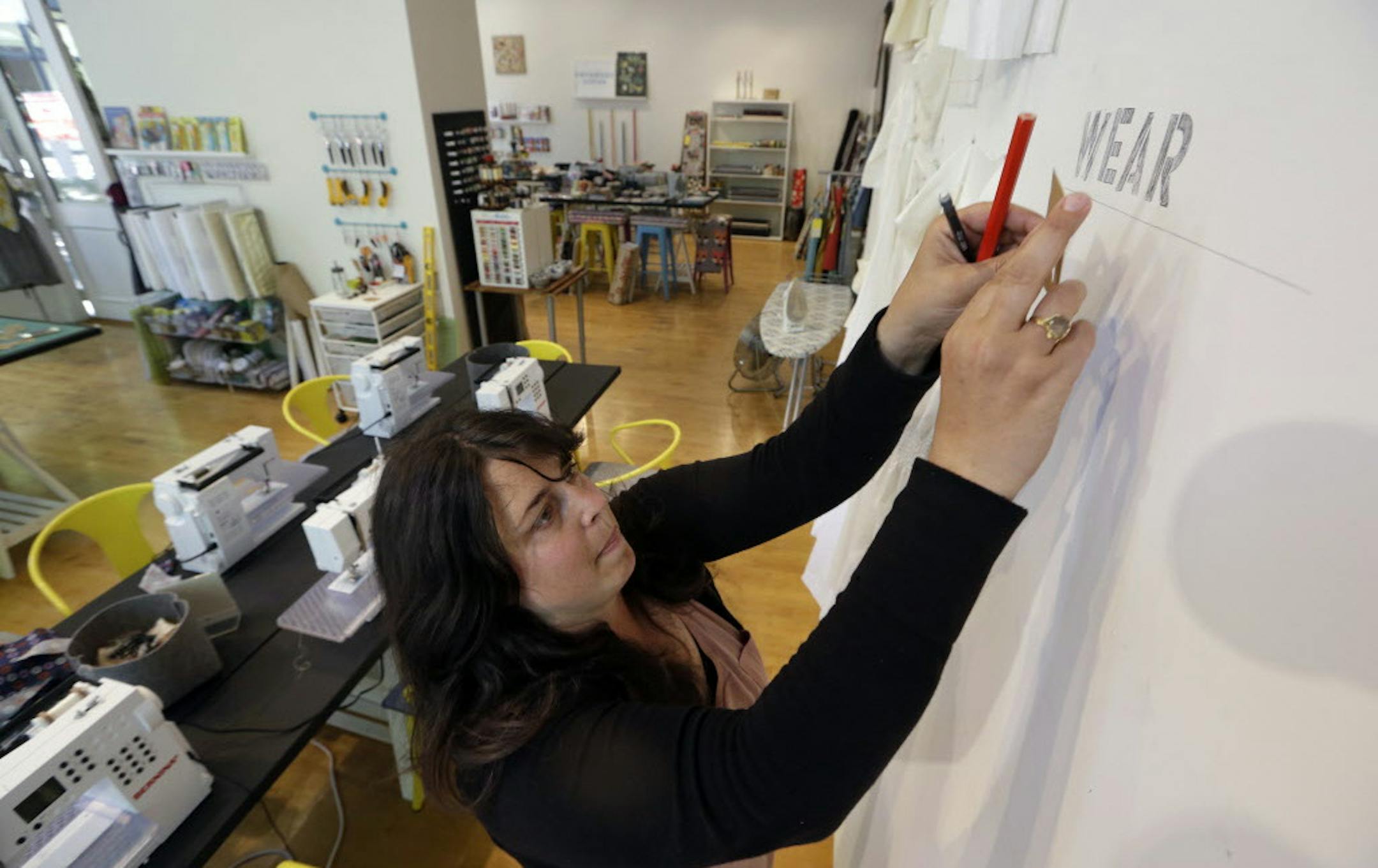 In this photo taken, Wednesday, July 1, 2015, Keli Faw works to put up a display in her shop, Drygoods Design, which she moved from the Ballard section of Seattle to the Pioneer Square neighborhood. Rent hikes are forcing small businesses to move and revamp. (AP Photo/Elaine Thompson)