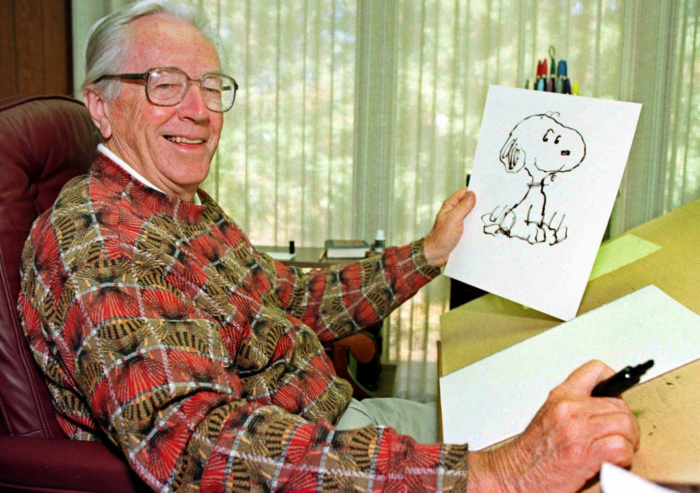 Cartoonist Charles Schulz displays a sketch of his beloved character "Snoopy" in his office in Santa Rosa, Calif.