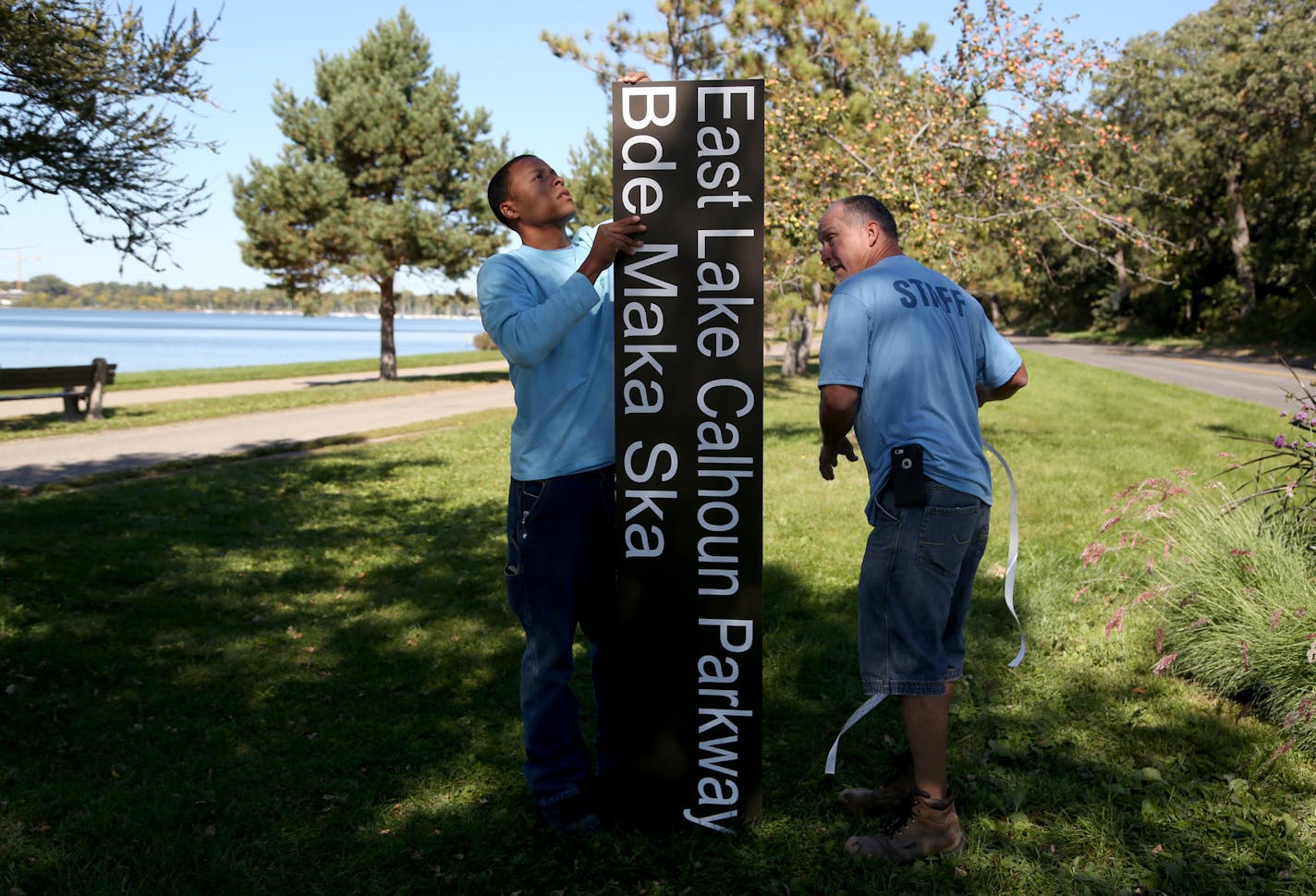 Workers install new signage at Lake Calhoun.