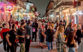 FILE - Partygoers on Bourbon Street on the last night before it was shut down for Mardi Gras in New Orleans, Feb. 11, 2021. After canceling many major