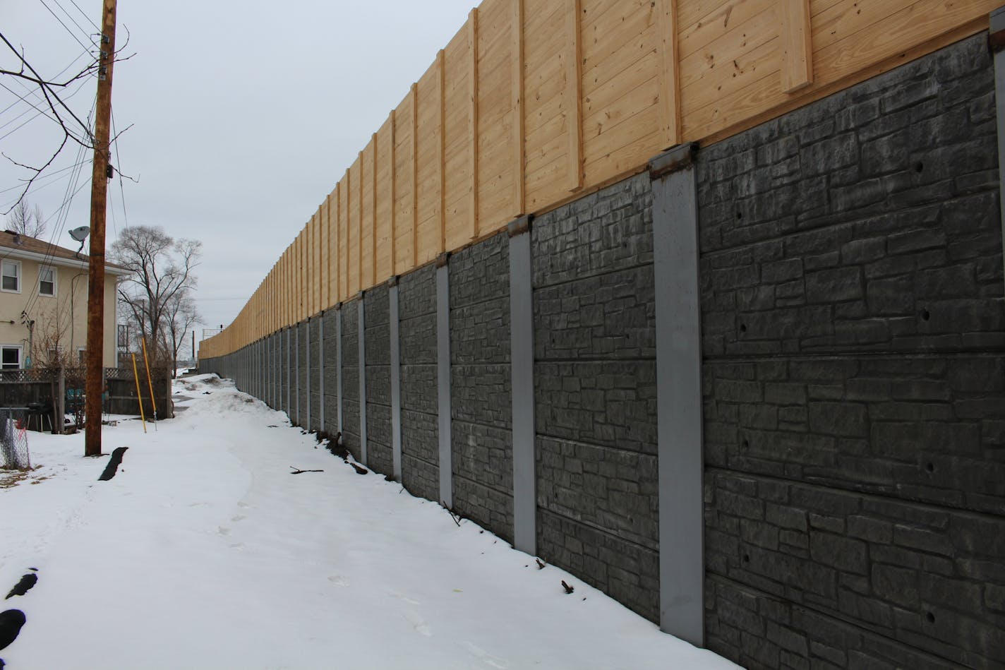 A new retaining wall and five-foot wooden sound barrier have been erected in place of trees in Northeast Minneapolis