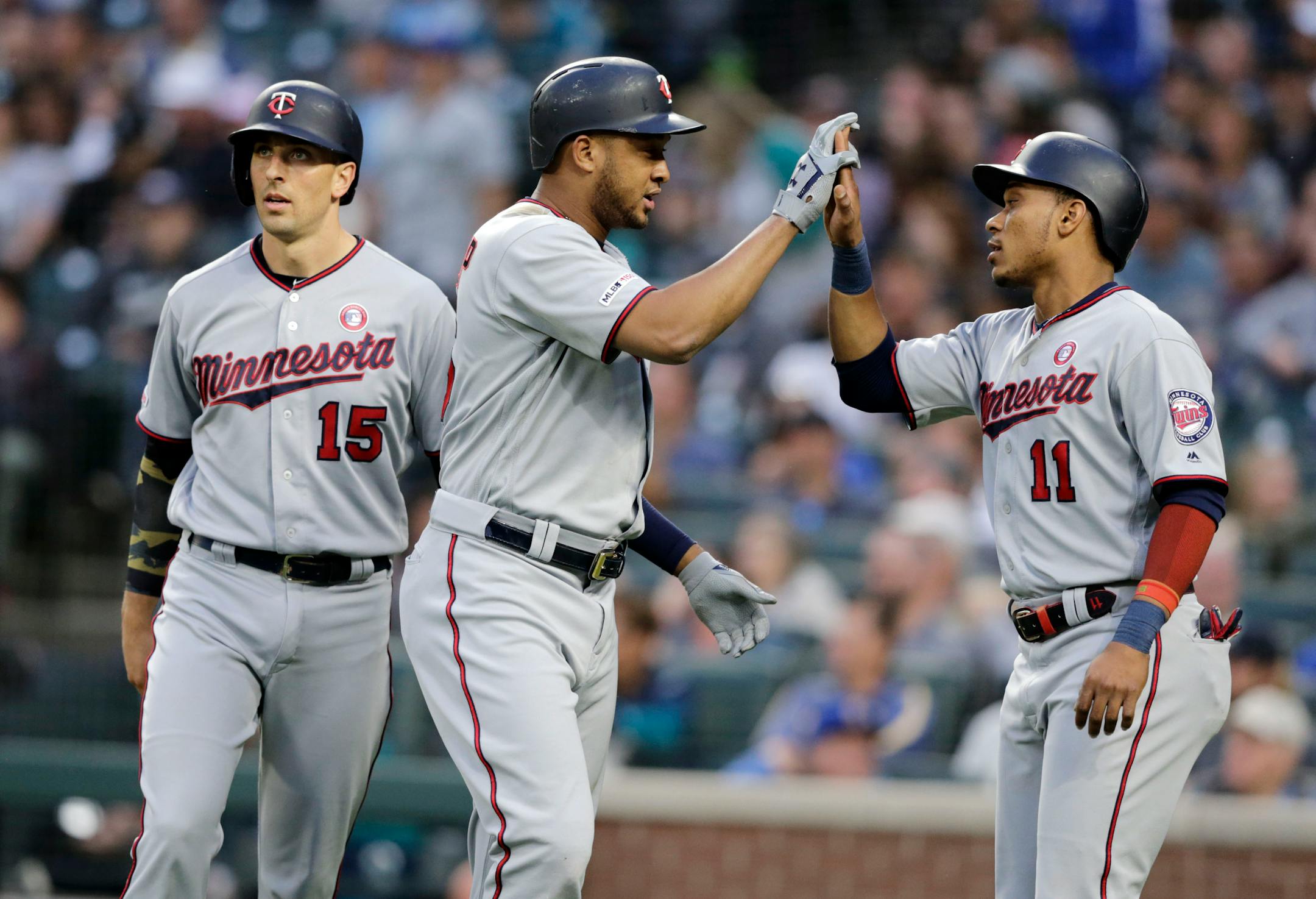 Minnesota Twins' Jonathan Schoop is greeted at home by Jorge Polanco, right, and Jason Castro, left, after hitting a three-run home run off Seattle Mariners' Parker Markel during the third inning of a baseball game Saturday, May 18, 2019, in Seattle. (AP Photo/John Froschauer)