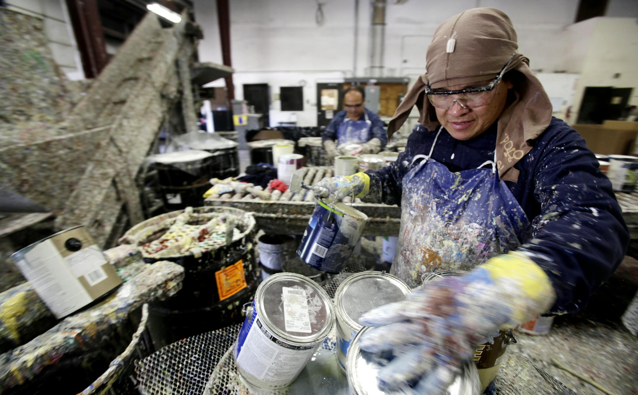 Dua Vue, right, and Nhia Thao, background, filled barrels with used paint at Amazon Paint, which sells 400,000 gallons a year and stands to sell more next year.