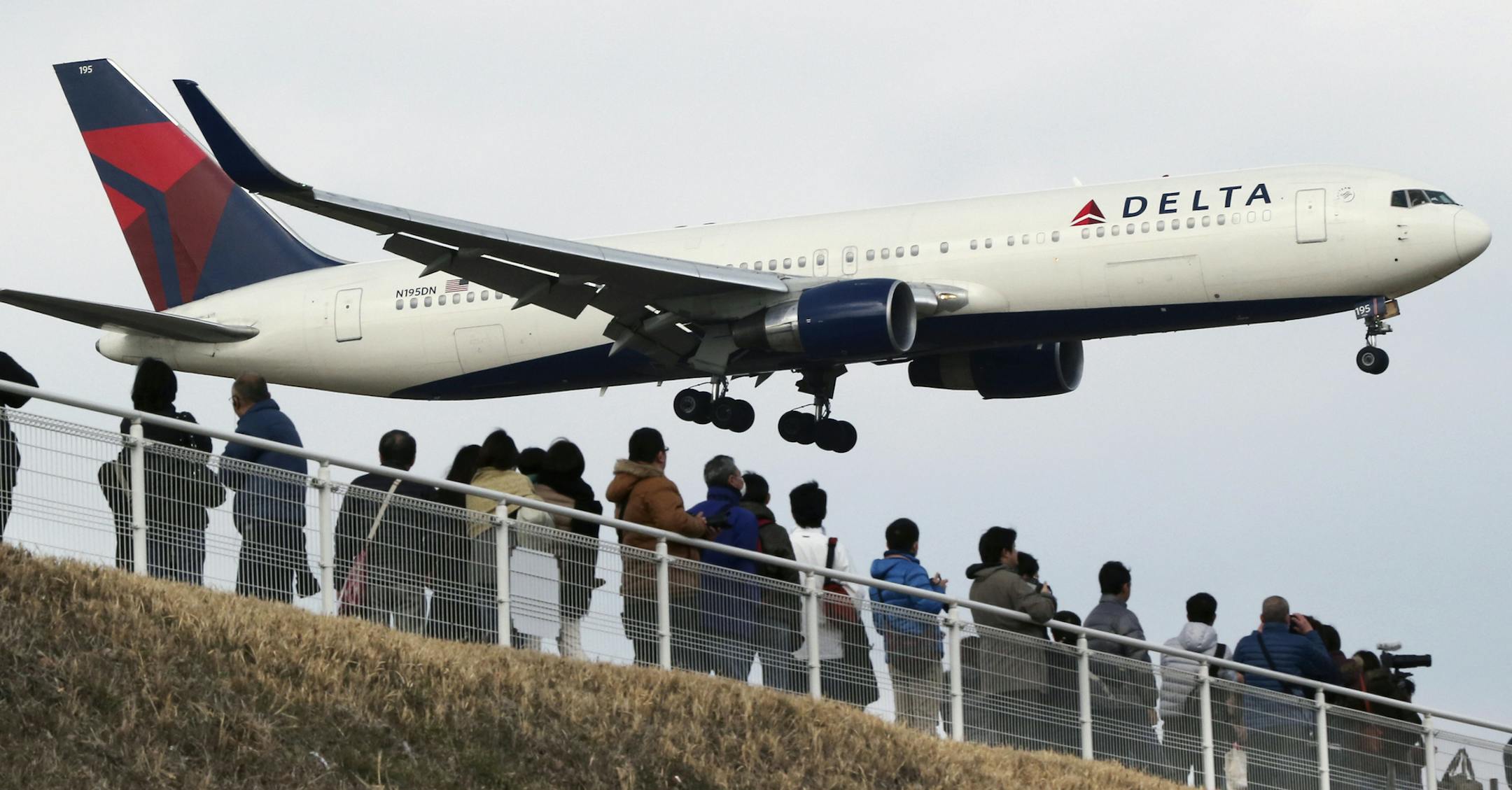 FILE - In this March 14, 2015 file photo, people watch a landing Delta Air Lines jet approach the Narita International Airport from a popular viewing spot at Sakuranoyama Park in Narita, east of Tokyo. Delta Air Lines reports quarterly financial results on Wednesday, April 15, 2015. (AP Photo/Koji Sasahara, File)