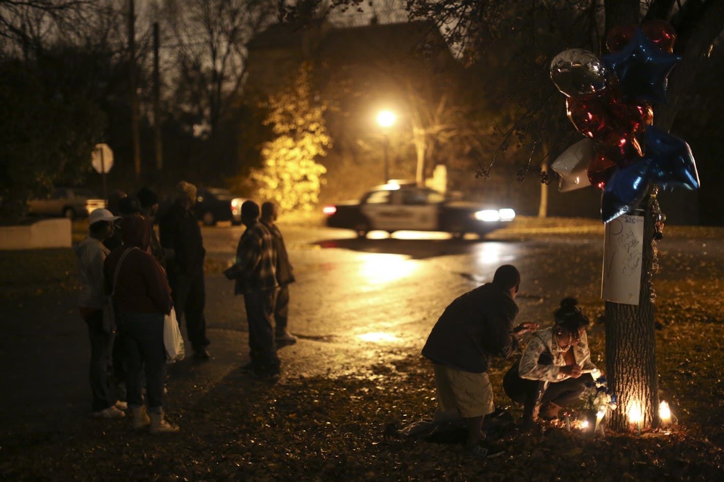 As a police car passed behind them, Kira Kyles and her brother, Kiron, tended to candles at a vigil for Victor Gaddy Wednesday night.