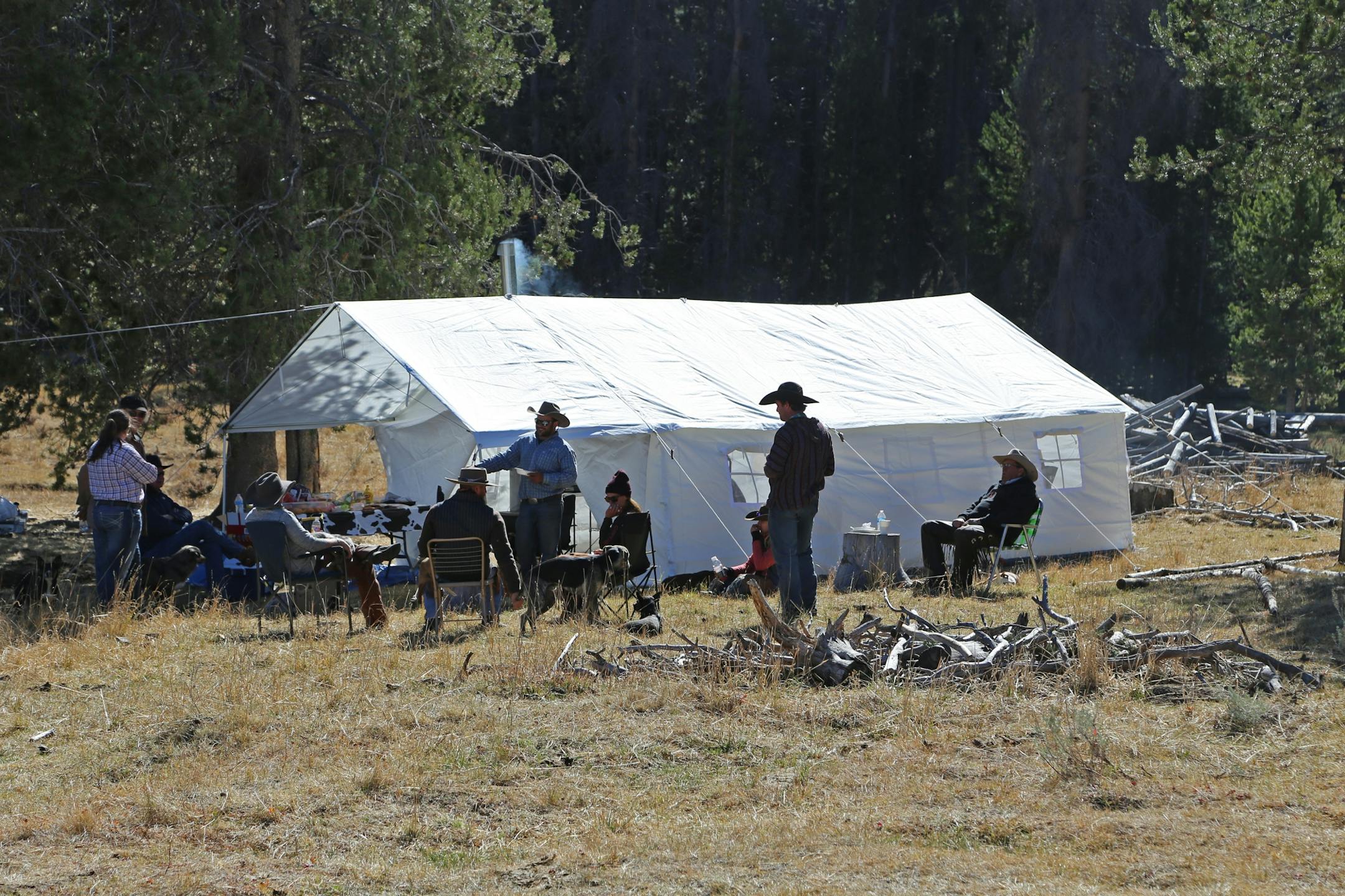 A cook tent is pitched in the mountains and serves as a gathering place for horseback riders at lunchtime. A wood stove inside the tent takes the chill off the day and helps snow- and rain-soaked riders dry off and warm up.