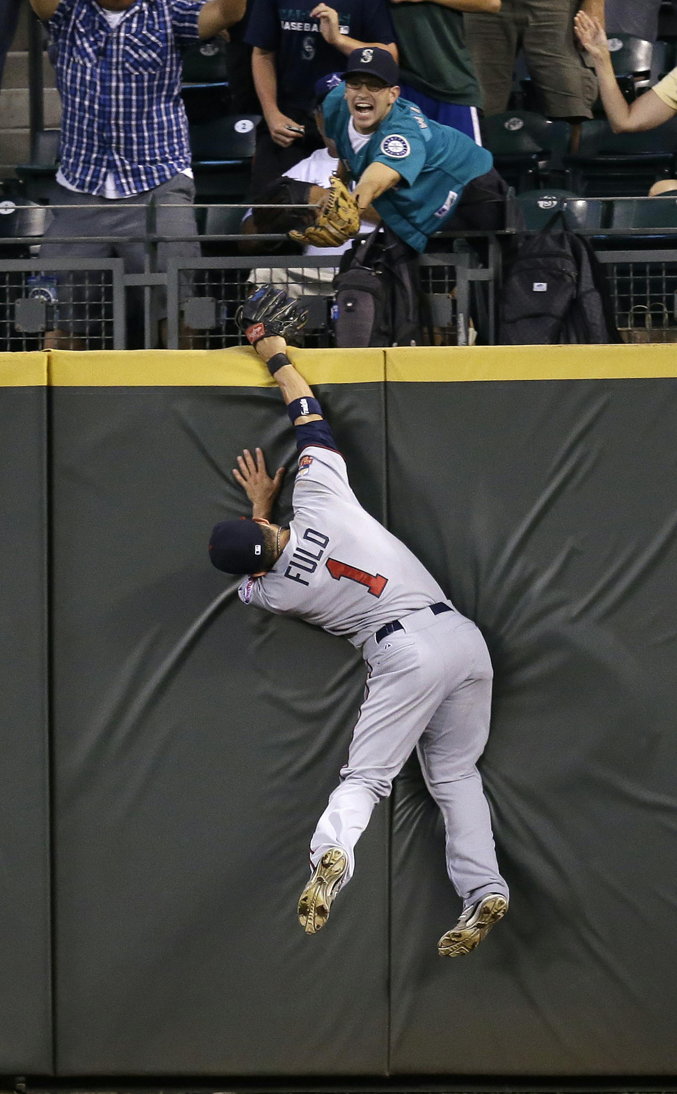 Minnesota Twins center fielder Sam Fuld slams into the outfield wall while chasing a deep fly ball from Seattle Mariners' Michael Saunders in the seventh inning of a baseball game Monday, July 7, 2014, in Seattle. Saunders had a home run on the play. (AP Photo/Elaine Thompson)