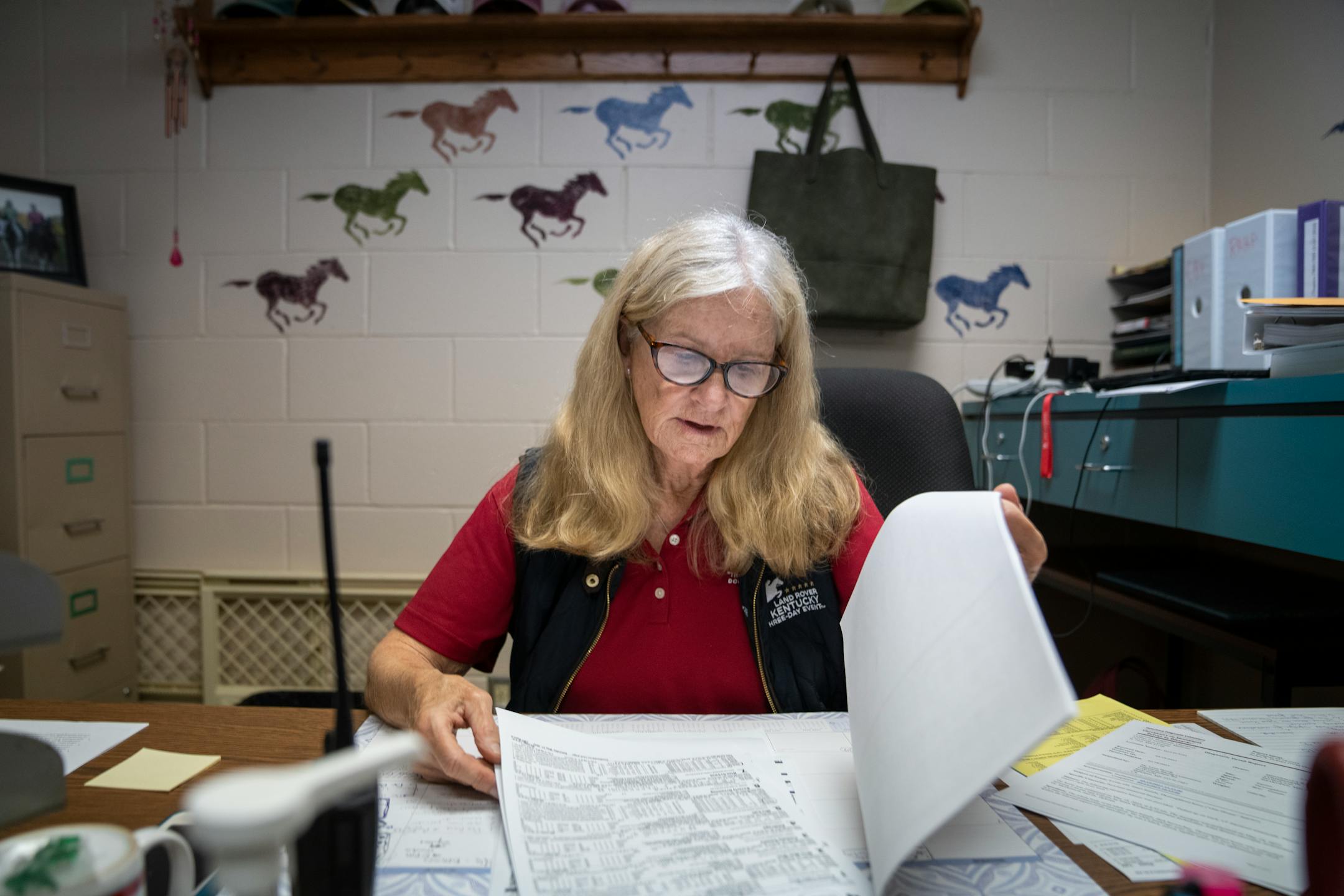 Dr. Lynn Hovda works in her office, looking through the information on every horse that will race, to get ready for race day at Canterbury Park in Shakopee, Minn.