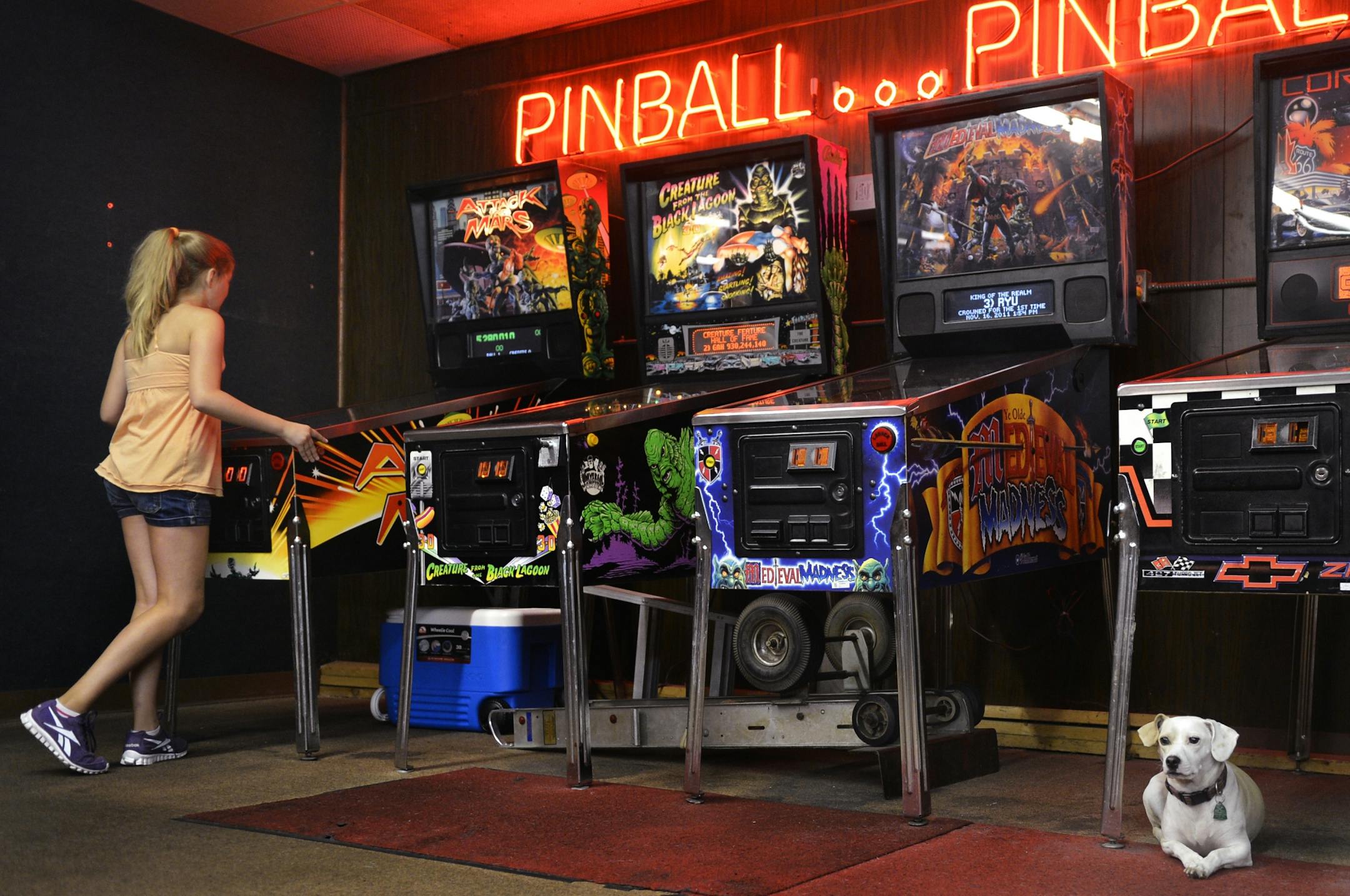 Jaida Schweiger, 10, visited SS Billiards with her parents. Owner Lloyd Olson's dog, Prada, likes to run around the legs of the machines.