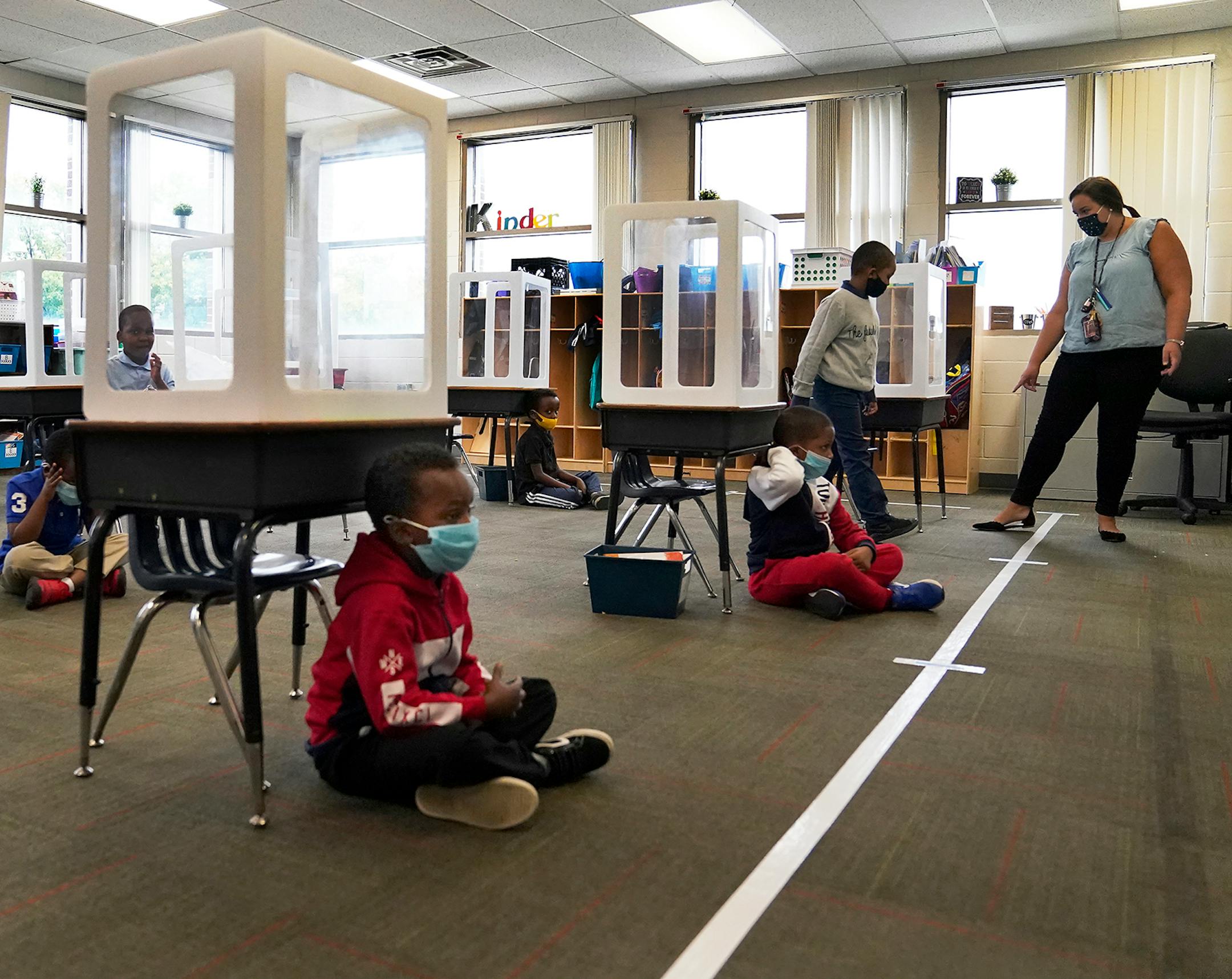 It was back to school for some students at Harvest Best Academy Tuesday in Minneapolis, but with masks, plastic barriers and other new precautions in the era of COVID-19. Here, Harvest Best Academy kindergarten teacher Sarah Swanson places students at a safe social distance during reading time in her learning pod.