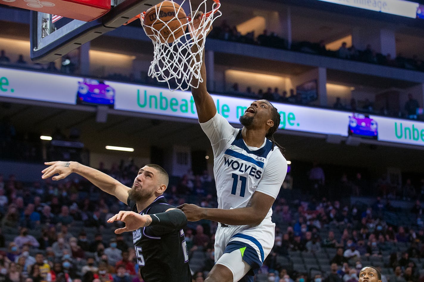 Minnesota Timberwolves center Naz Reid (11) dunks over Sacramento Kings center Alex Len during the first quarter of an NBA basketball game in Sacramento, Calif., Tuesday, Feb. 8, 2022. (AP Photo/Randall Benton)