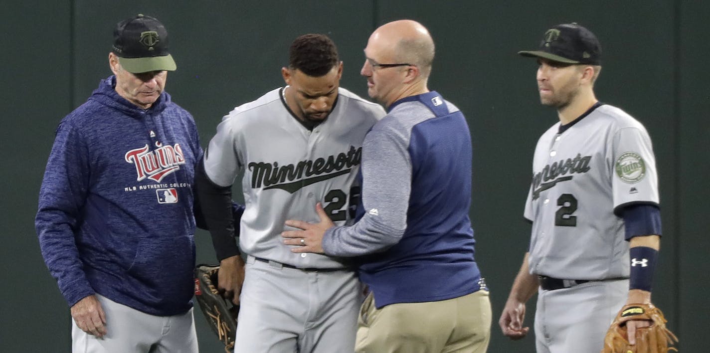 Minnesota Twins center fielder Byron Buxton, second from left, is attended to by head trainer Tony Leo, second from right, after he crashed into the wall while trying to catch a two-run home run hit by Seattle Mariners' Nelson Cruz during the sixth inning of a baseball game, Saturday, May 26, 2018, in Seattle. (AP Photo/Ted S. Warren)