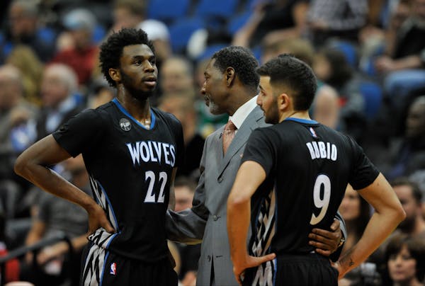 Minnesota Timberwolves interim head coach Sam Mitchell speaks with guard Andrew Wiggins (22) and guard Ricky Rubio (9) during a game against the Nugge