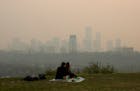 Smoke from wildfires blankets the city as a couple has a picnic in Edmonton, Alberta, Saturday, May 11, 2024.