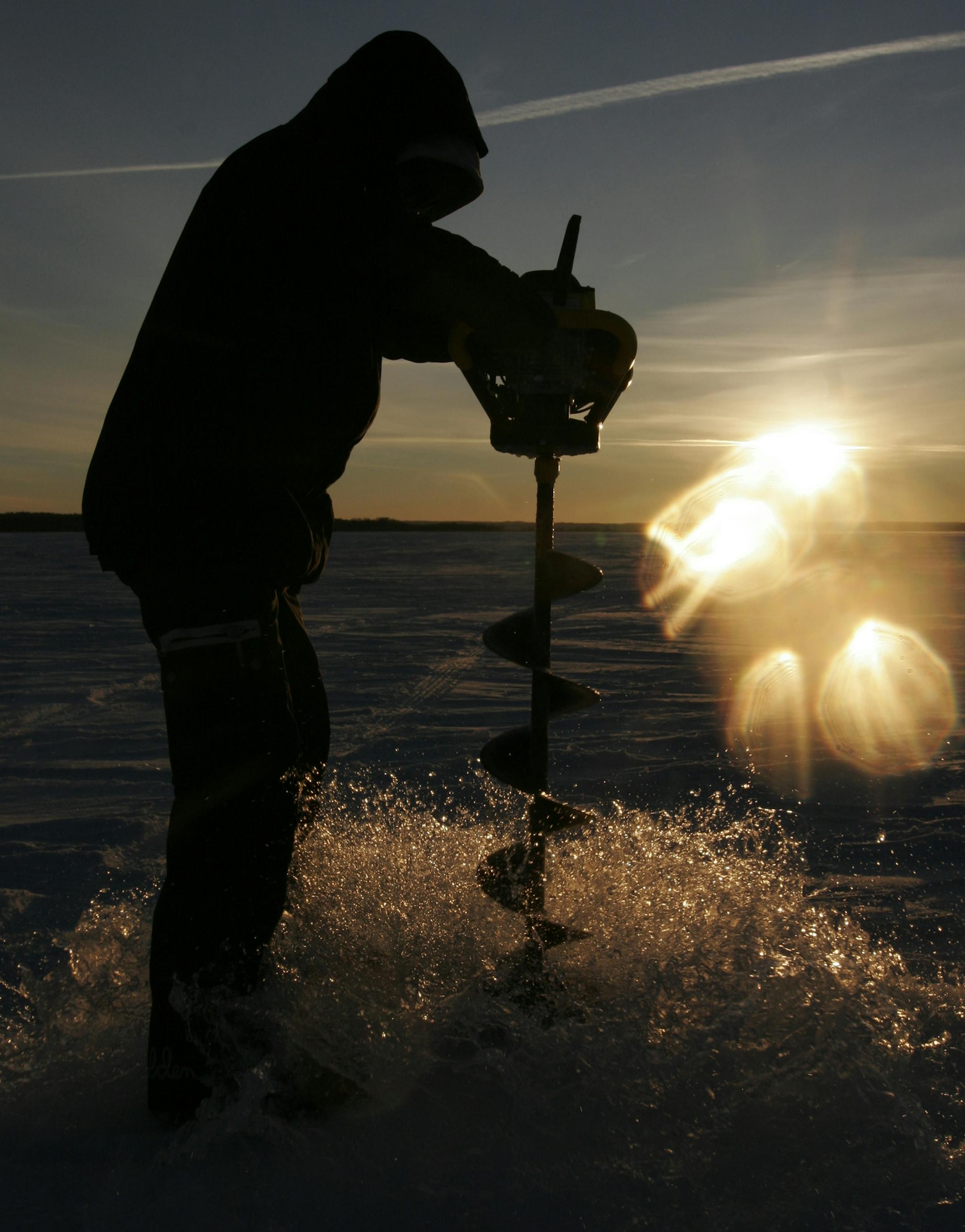 The setting sun reflected off the ice and snow as Nate Rendulich pulled up an auger full of water after drilling an ice fishing hole on Leech Lake.