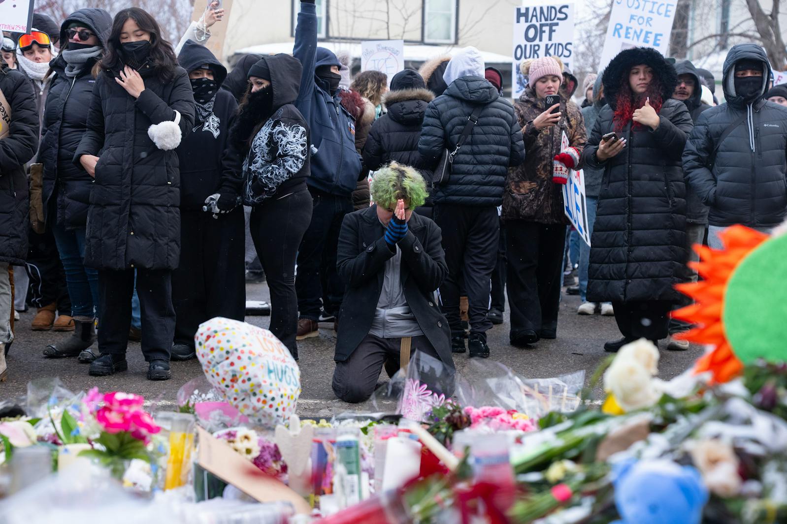 A community member kneels at the memorial to Renee Good in Minneapolis on Jan. 10.