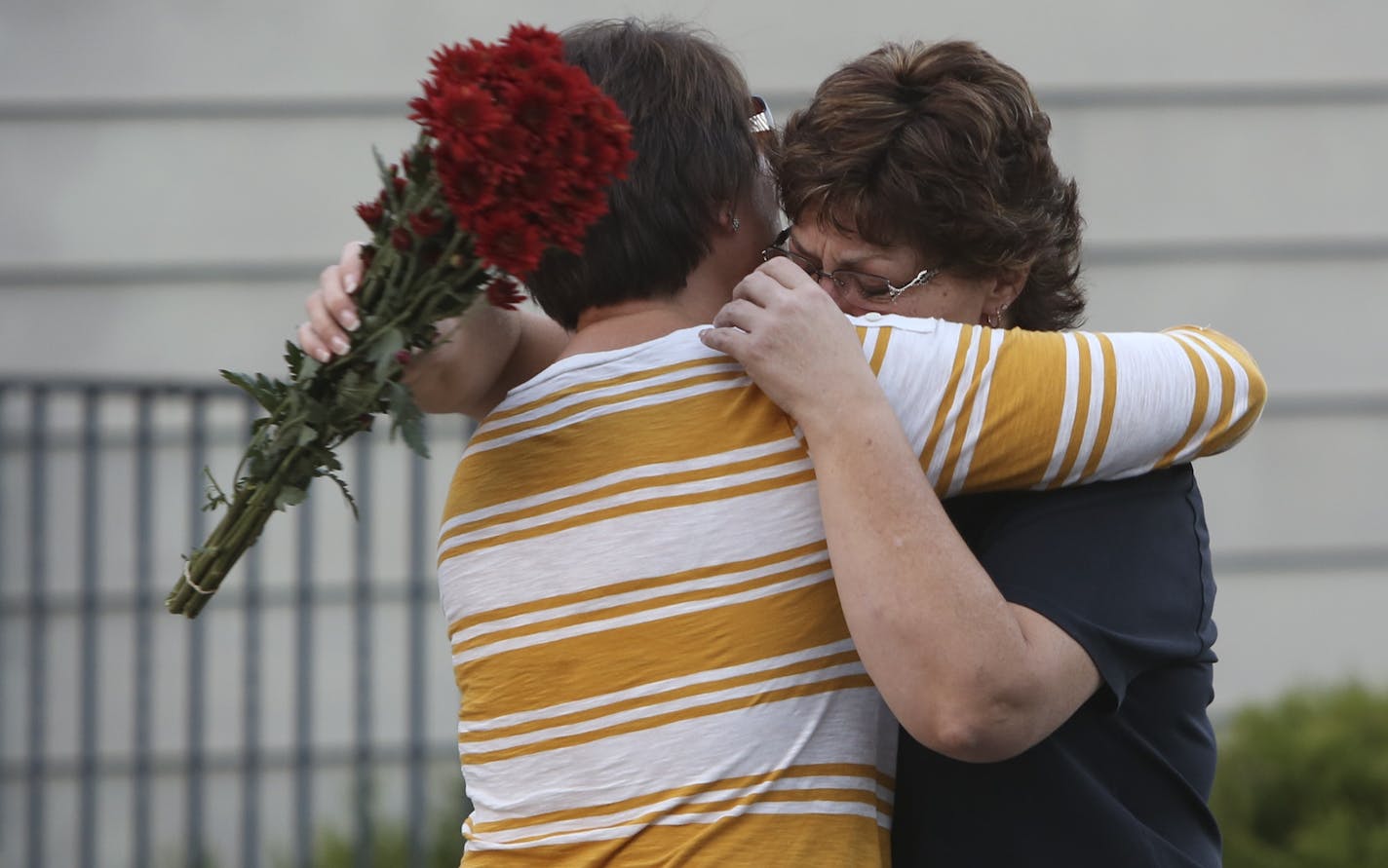 Lori Nix, sister of Ron Edberg, hugged another family member near the memorial made for the victims in front of Accent Signage Systems in Minneapolis, Min., Saturday September 29, 2012. Edberg was one of the employees that lost his life Thursday at the hands of Andrew Engeldinger.