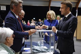 French President Emmanuel Macron, right, votes for the second round of the legislative elections in Le Touquet-Paris-Plage, northern France, Sunday Ju