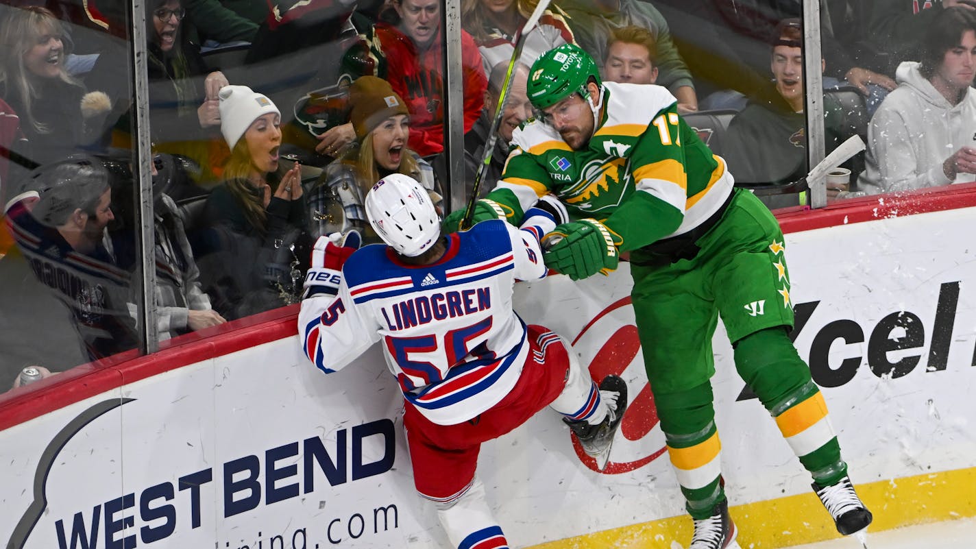 Minnesota Wild left wing Marcus Foligno, right, checks New York Rangers defenseman Ryan Lindgren into the boards during third period of an NHL hockey game Saturday, Nov. 4, 2023, in St. Paul, Minn. The Wild won 5-4 in a shootout. (AP Photo/Craig Lassig)