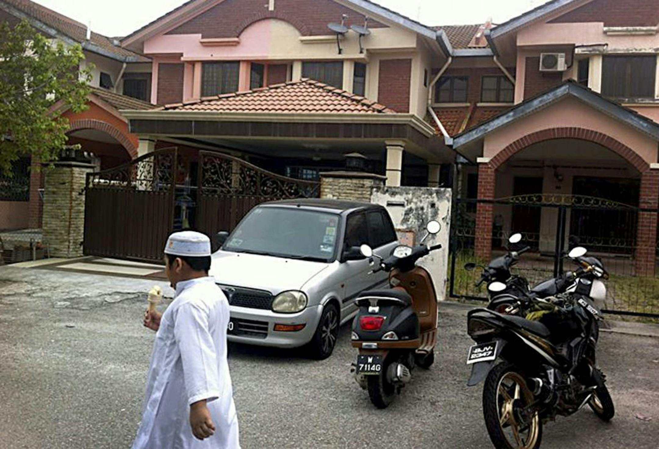 A Muslim boy leaves a mosque after Friday prayers, just down the road from the home of Fariq Abdul Hamid, co-pilot of the missing Malaysia Airlines jetliner MH370, center, Friday, March 14, 2014 in Shah Alam, Malaysia.