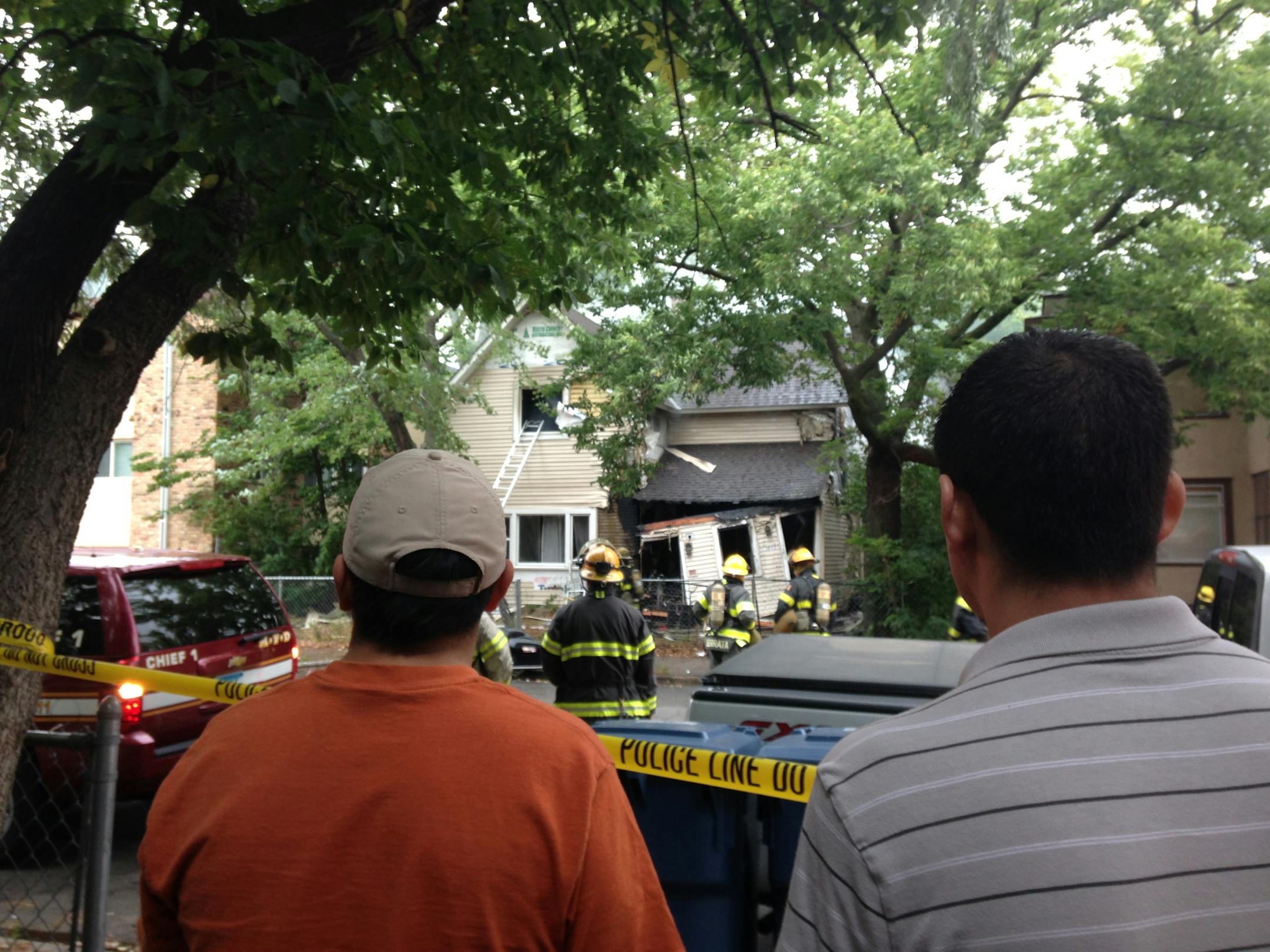 Neighbors watch firefighters at the scene of a house fire and explosion at Grand Ave. and 30th St. in south Minneapolis on Tuesday.