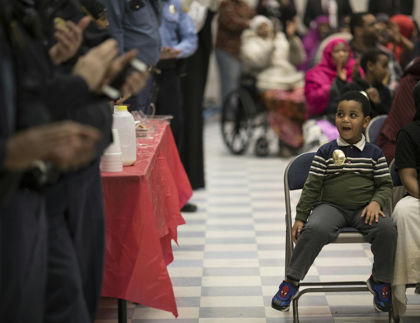 Mahfouz Badrr, 3, made silly faces with a St. Paul police officer standing nearby as he wore a sticker police badge during a meeting between the mayor, the police and the immigrant community at Skyline Towers on Wednesday.