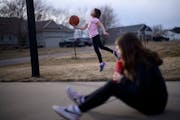 Zoey Voigt, 10, tries a trick shot with a basketball while her sister Abigail, 11, take a drink Wednesday in St. Augusta. The two sisters, both born w