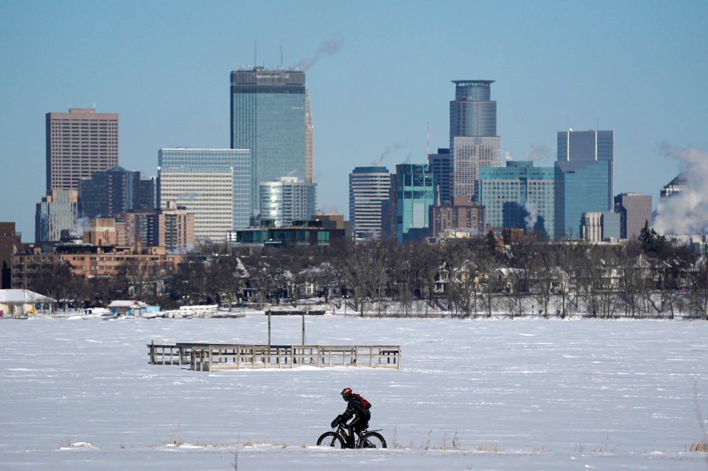 A cyclist decked out in cold weather gear rode past the city skyline and a frozen Bde Maka Ska in Minneapolis.