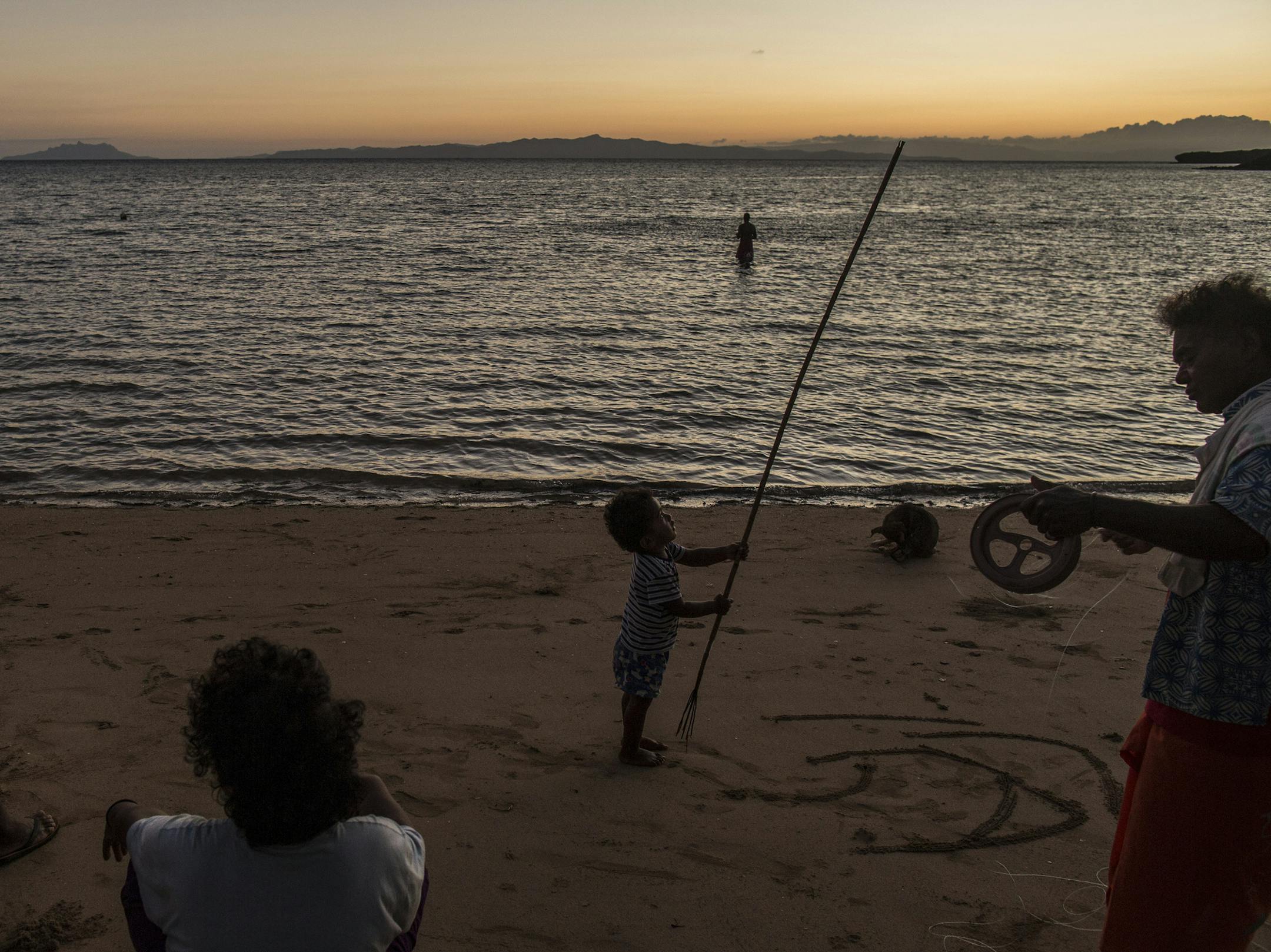 People gather at sunset in the village of Denimanu on the Fijian Island of Yadua, Nov. 17, 2016. The skills for hunting turtles, passed down through the generations on the island, come in handy for tracking and protecting them from illegal harvesting. (Lam Yik Fei/The New York Times)