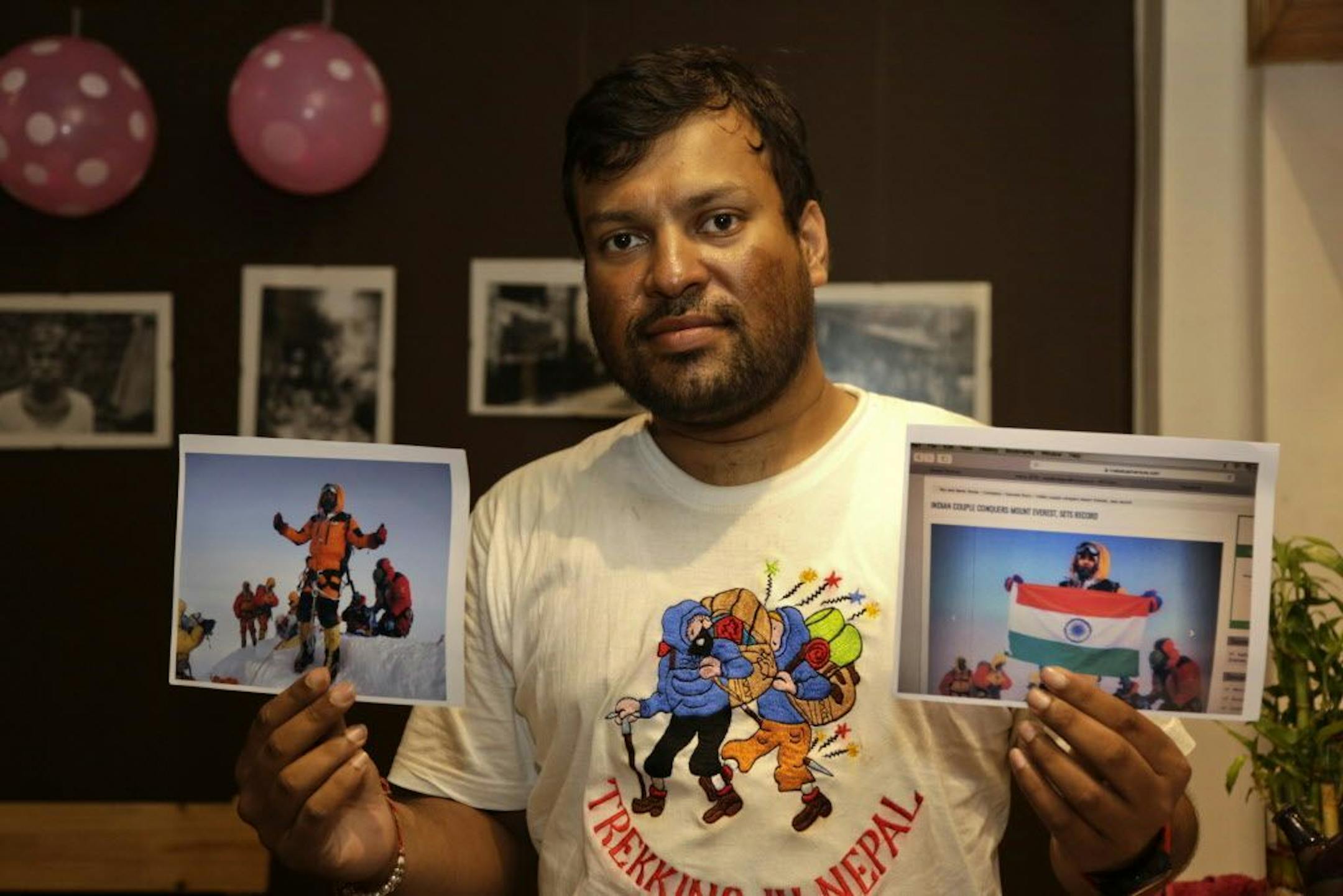 FILE- In this July 4, 2016 file photo, Indian climber, Satyarup Sidhantha holds on his right hand a photograph that shows him on Mount Everest, along with what he says is an altered version of the same used by an Indian couple to make it appear they were on the summit.
