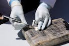 A technician cuts open a package of cocaine