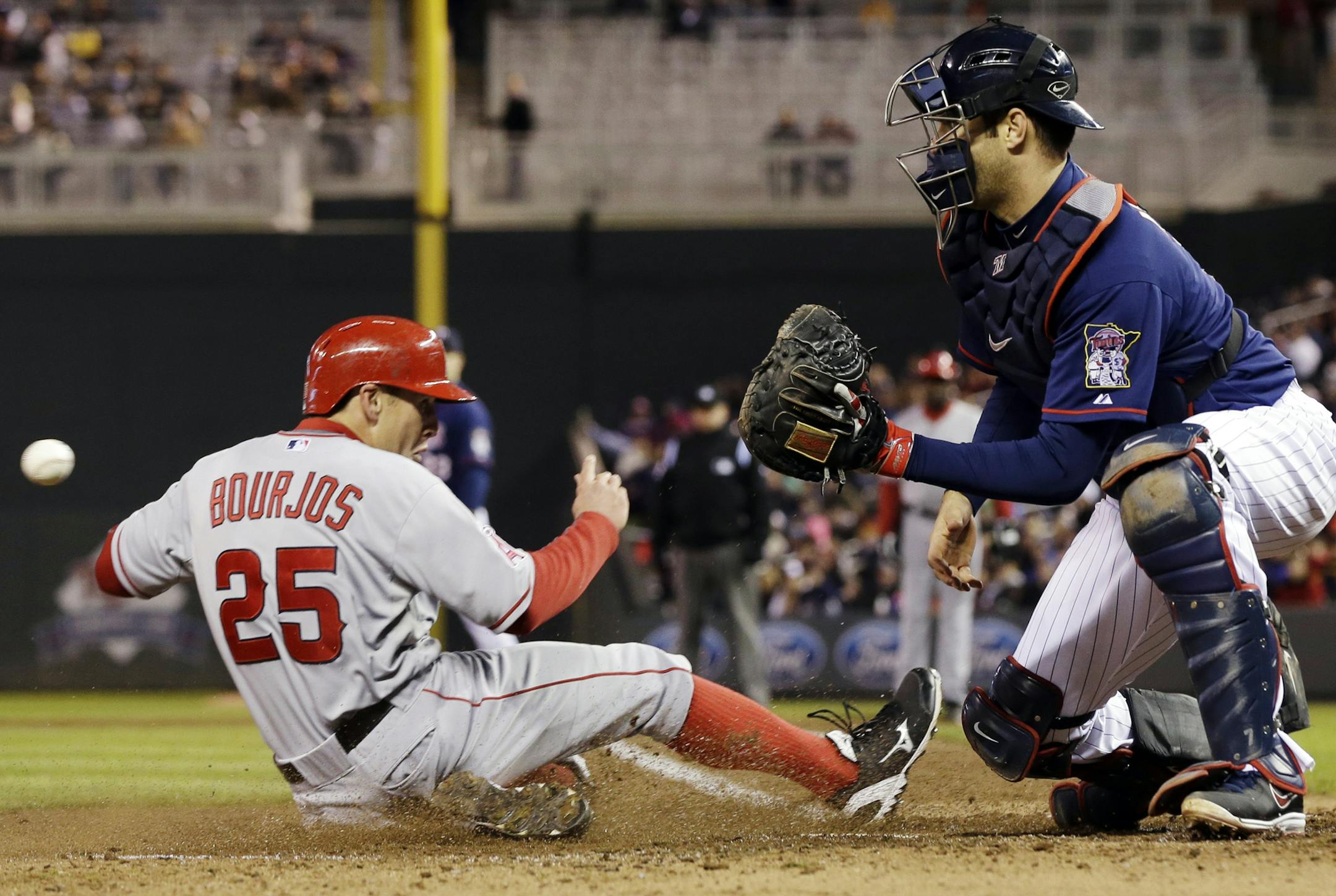 Los Angeles Angels' Peter Bourjos, left, beats the throw to Minnesota Twins catcher Joe Mauer to score on a hit by Angels' Albert Pujols in the third inning of a baseball game, Tuesday, April 16, 2013, in Minneapolis. (AP Photo/Jim Mone)