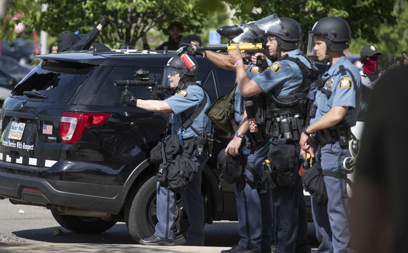 St. Paul Police officers took cover as protesters walked toward them at the Super Target .