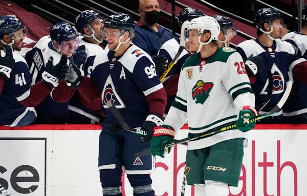 Avalanche right wing Mikko Rantanen smiles as he is congratulated while passing the team after scoring a goal as Wild defenseman Jonas Brodin looks on