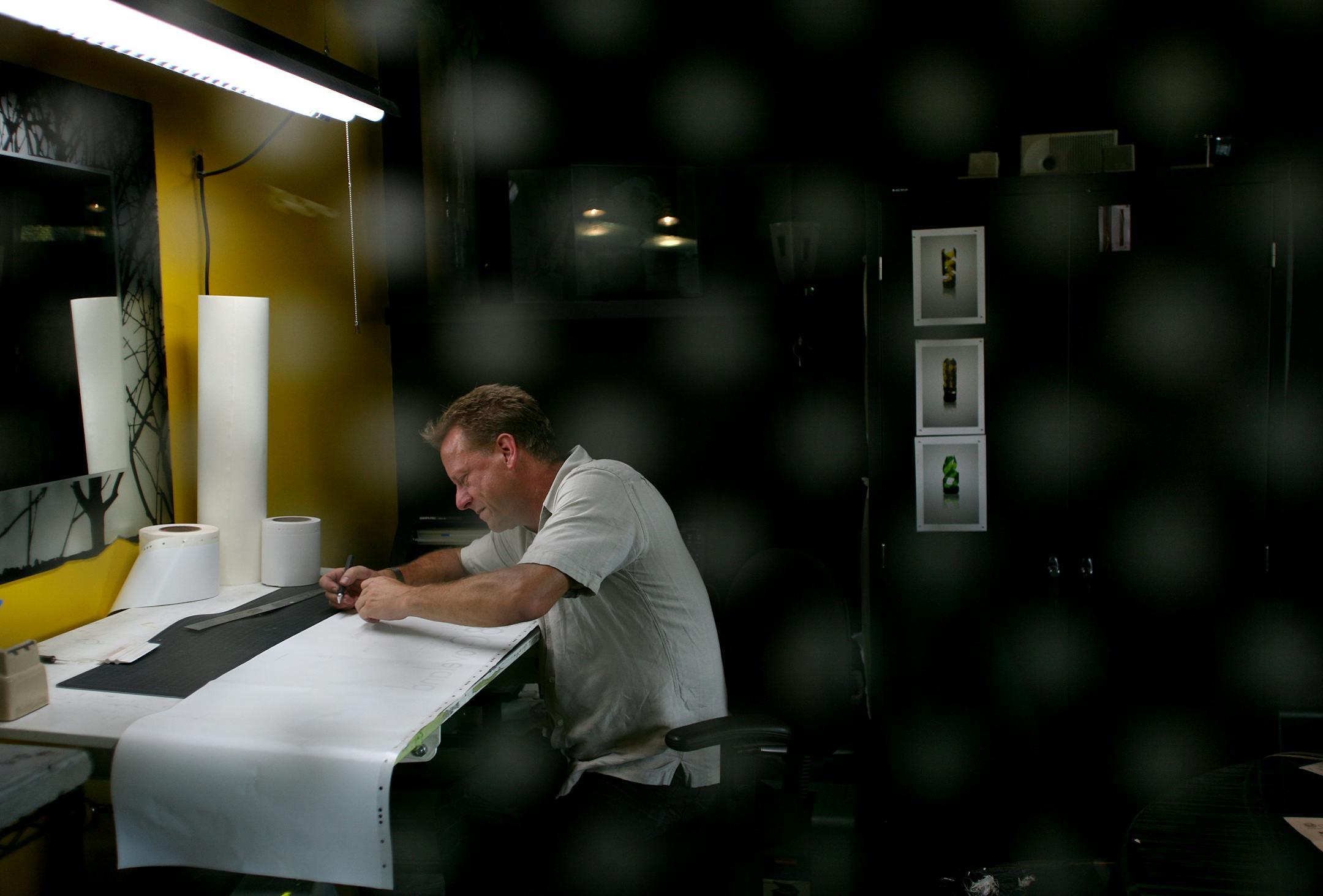 Sandblast artist Kerry Dikken worked in his Nicollet Avenue studio on a design that will be sandblasted into a piece of glass and eventually displayed at a downtown condominium. Dikken was making the vinyl mask that will cover the portions of glass he doesn't want to be sandblasted.