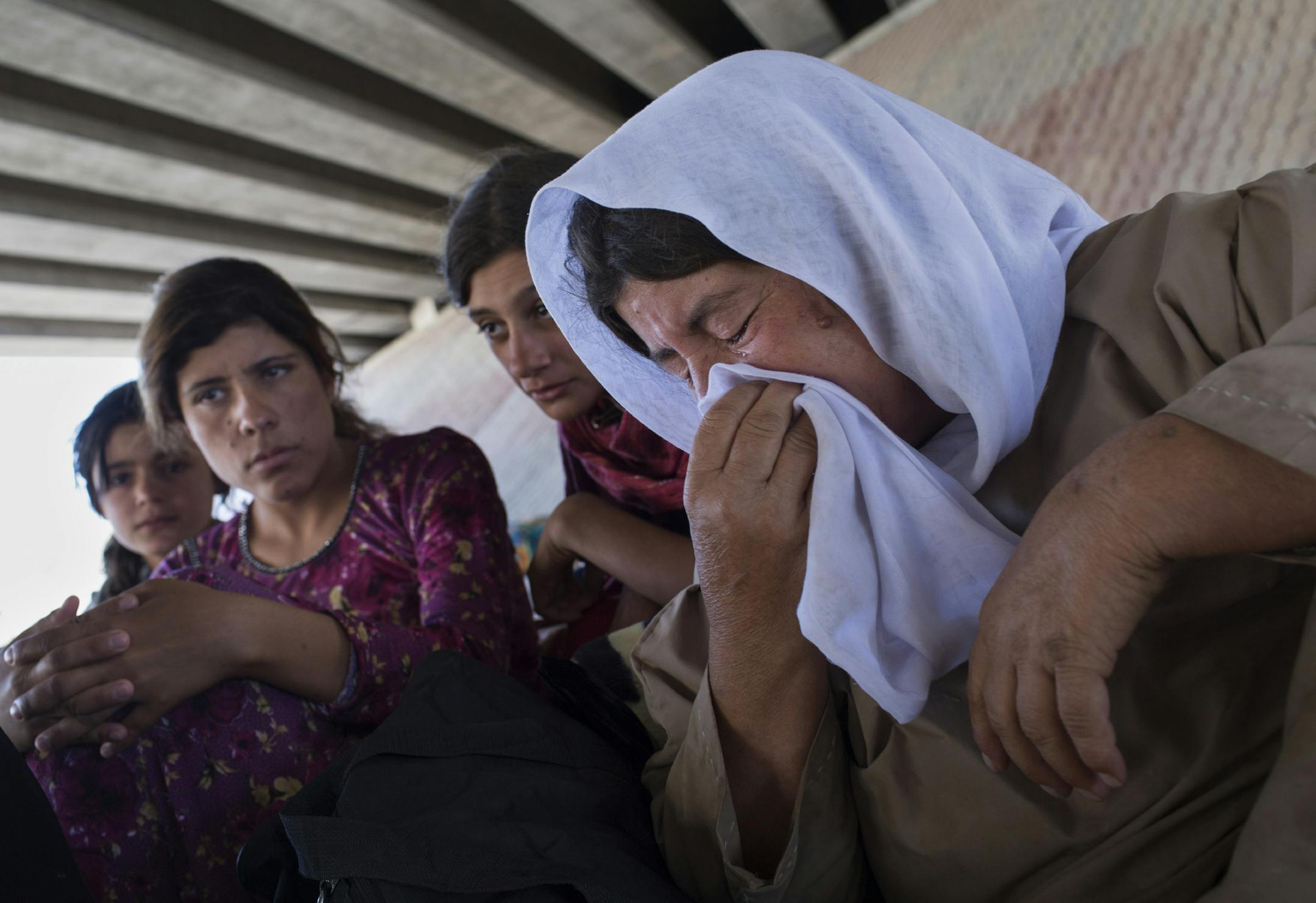 Yazidi people who have fled from Islamic State forces take shelter by the roadside in Dohuk, Iraq, Aug. 8, 2014. Many members of religious minorities in northern Iraq have fled to Kurdish territory, where American aircraft have conducted bombing missions to assist the local pesh merga in combat against the Islamic State fighters. (Adam Ferguson/The New York Times)