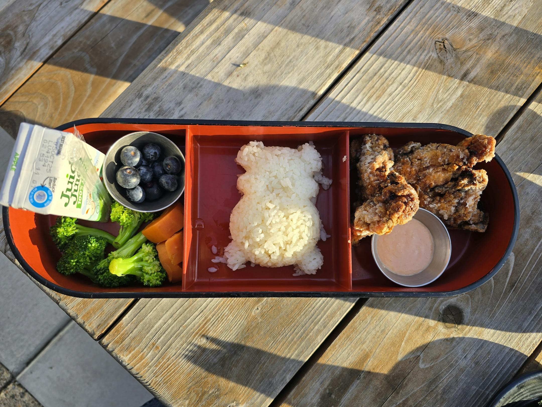 A bento box with three compartments each containing items from the kids menu