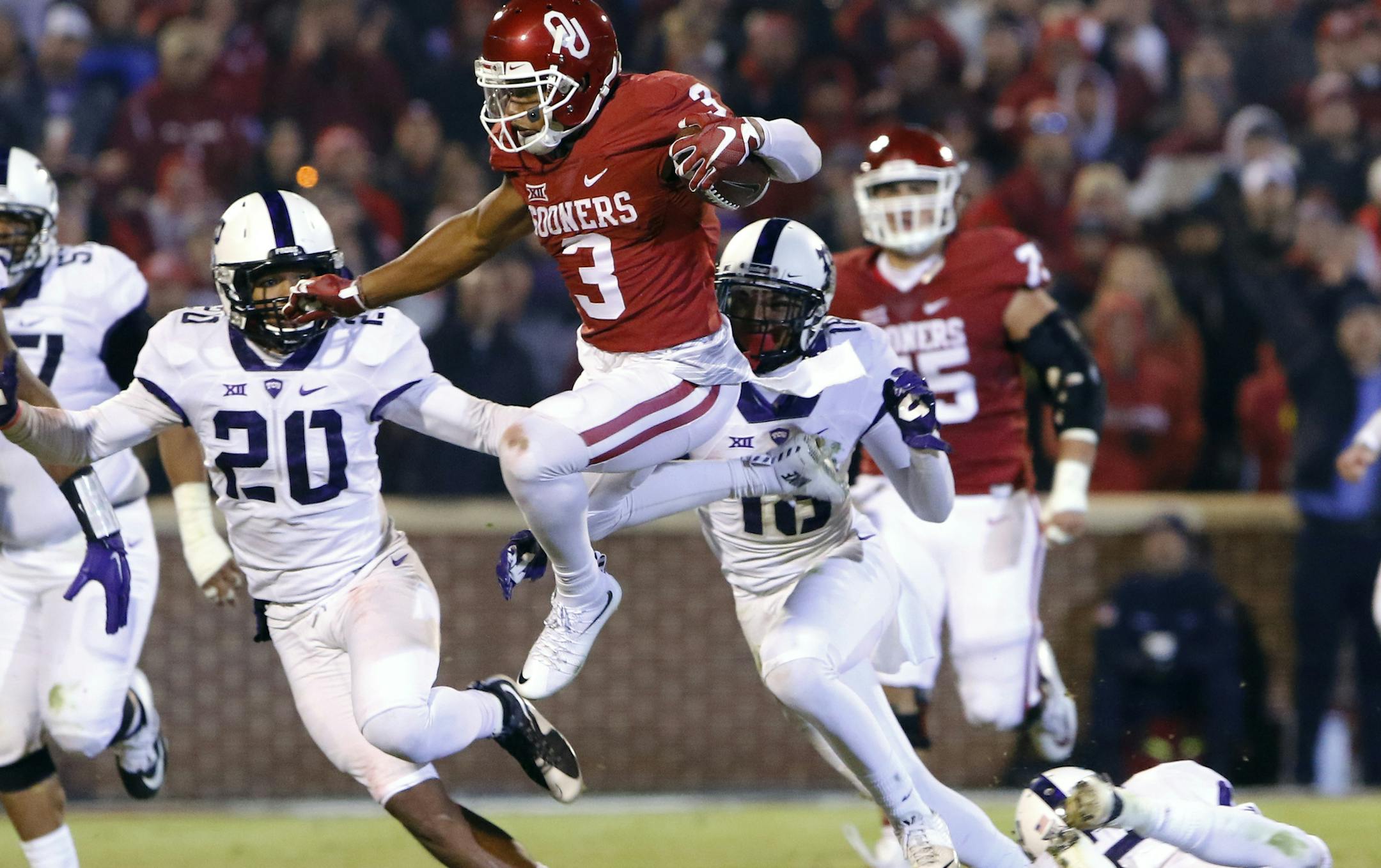Oklahoma wide receiver Sterling Shepard (3) leaps to avoid as TCU linebacker Montrel Wilson (20) and others chase him during the third quarter of an NCAA college football game in Norman, Okla., Saturday, Nov. 21, 2015. Oklahoma won 30-29. (AP Photo/Alonzo Adams)