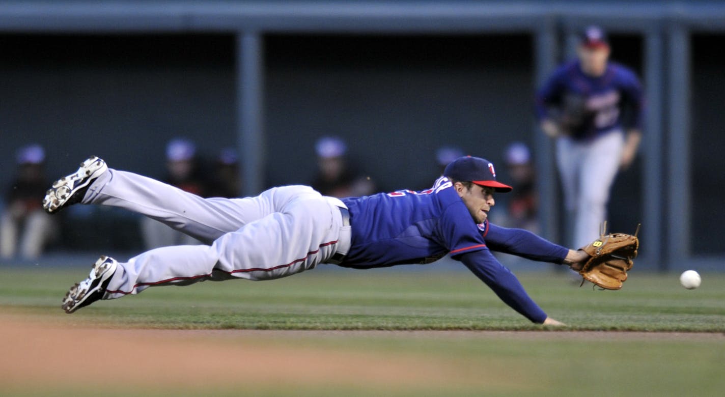 Minnesota Twins second baseman Brian Dozier dives for a ground ball hit by Baltimore Orioles Manny Machado in the first inning of a baseball game on Saturday, April 6, 2013, in Baltimore. Machado earned a single on the play. (AP Photo/Gail Burton)