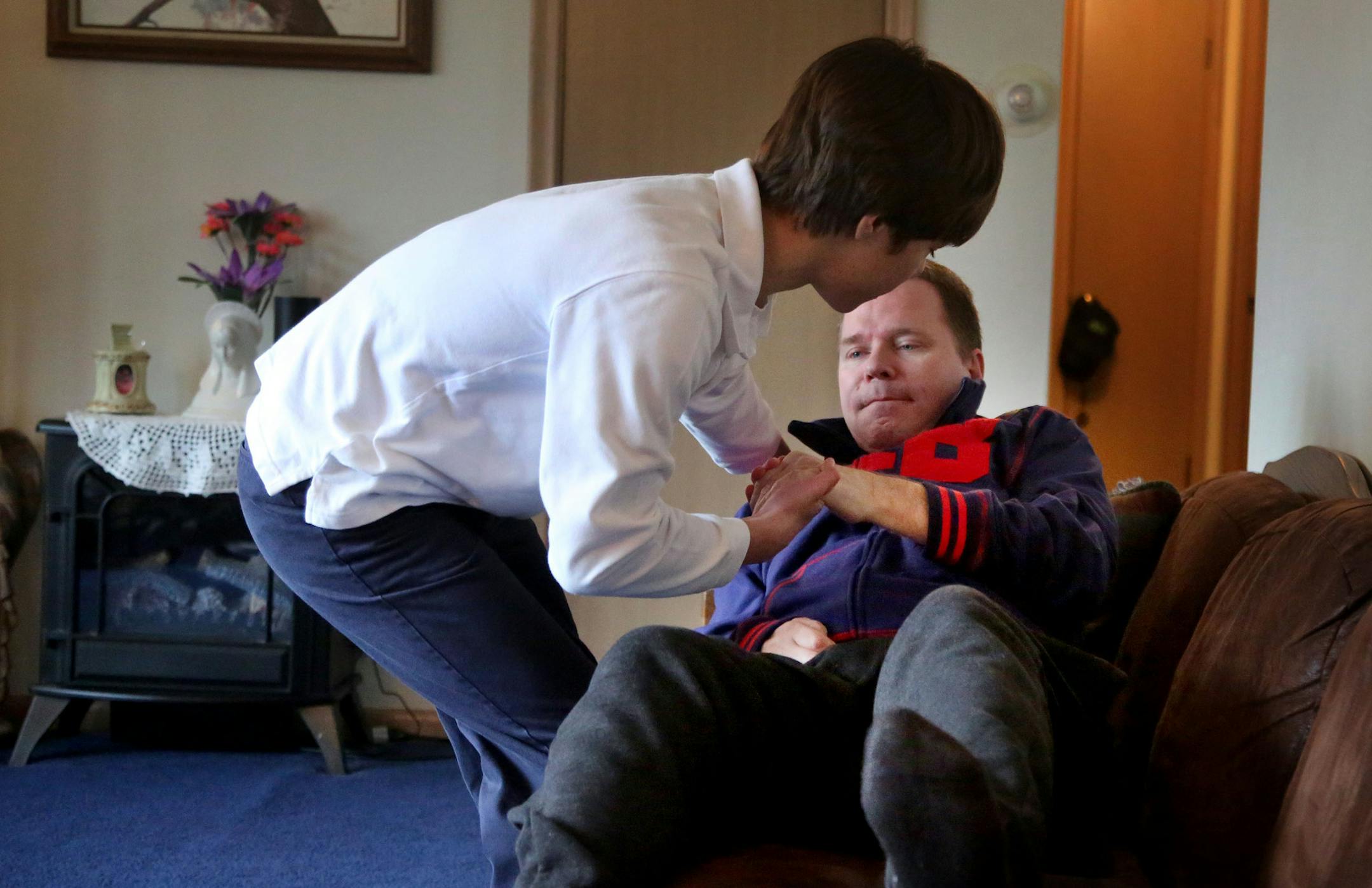 On a day Bob White, 47, who has A.L.S., volunteers at the school of his son, Kieran, 13, washes his fatherís hair in the shower before brushing Bobís hair. His father drives them to school later in the morning, and because of the physical deterioration the disease has caused in Bobís limbs, Kieran shifts the red Hyundai Elantra from park into reverse for his father to back out of the driveway. The incurable condition has forced Kieran into a part-time role as a child caregiver.](D
