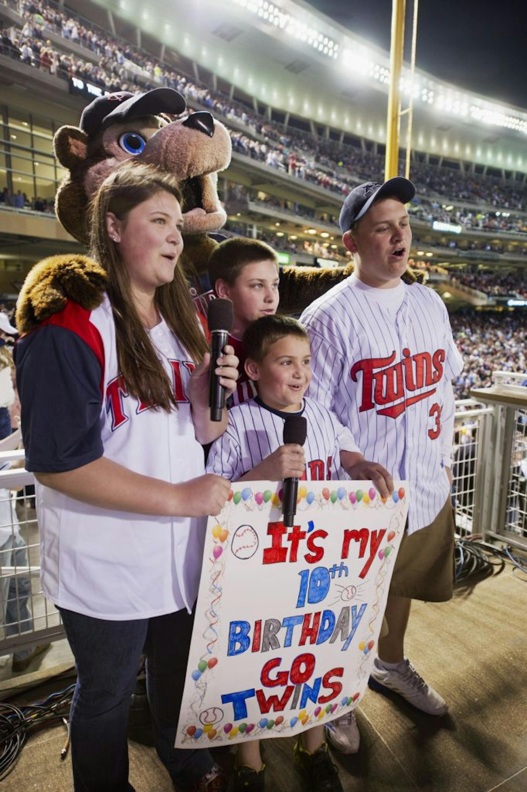Singing "Take Me Out to the Ballpark" in the middle of the 7th inning is the Wyers family, with help from the Twins mascot, T.C. Left to right are Jennifer, Thomas, Patrick, and Nick Wyers.