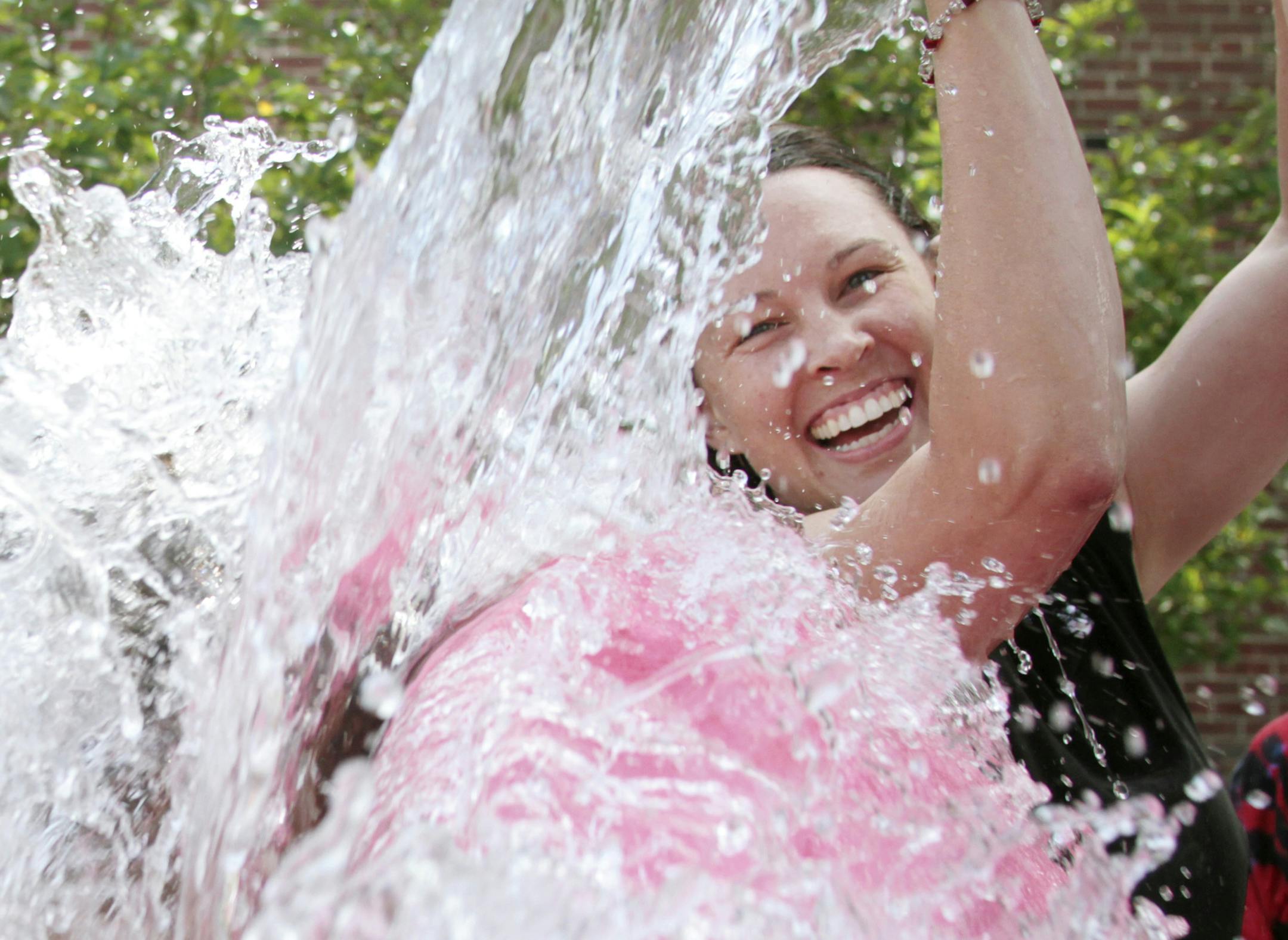 Richfield School District Administrator Tara Villalobos smiles as she dumps a bucket of ice water onto a fellow participant of the ALS ice bucket challenge outside Richfield Elementary School in Richfield, Wis. Nearly 30 members from the school district and family members participated raising more than $233.00 for ALS research. (AP Photo/West Bend Daily News, John Ehlke)