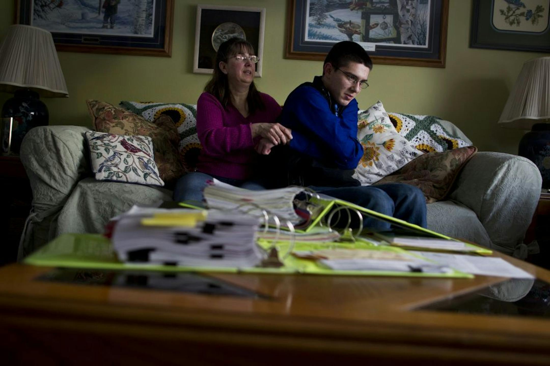 Christine Riege held he son Gary's arms as they demonstrated what was the most common restraint he was put in at school as a young child. On the table in front of them were piles of documents of the restraints. They were at their home in Cottage Grove, Minn. on March 22, 2013.