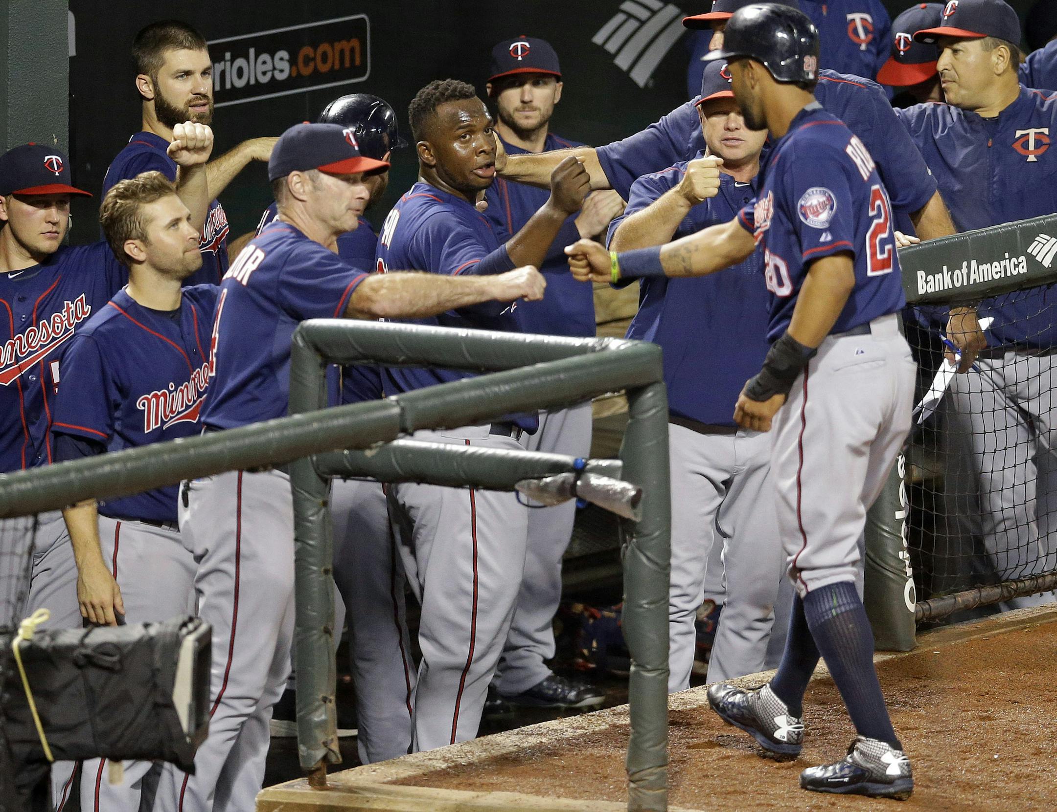 Teammates greet Minnesota Twins' Eddie Rosario, right, as he enters the dugout after scoring on a single by Kurt Suzuki.