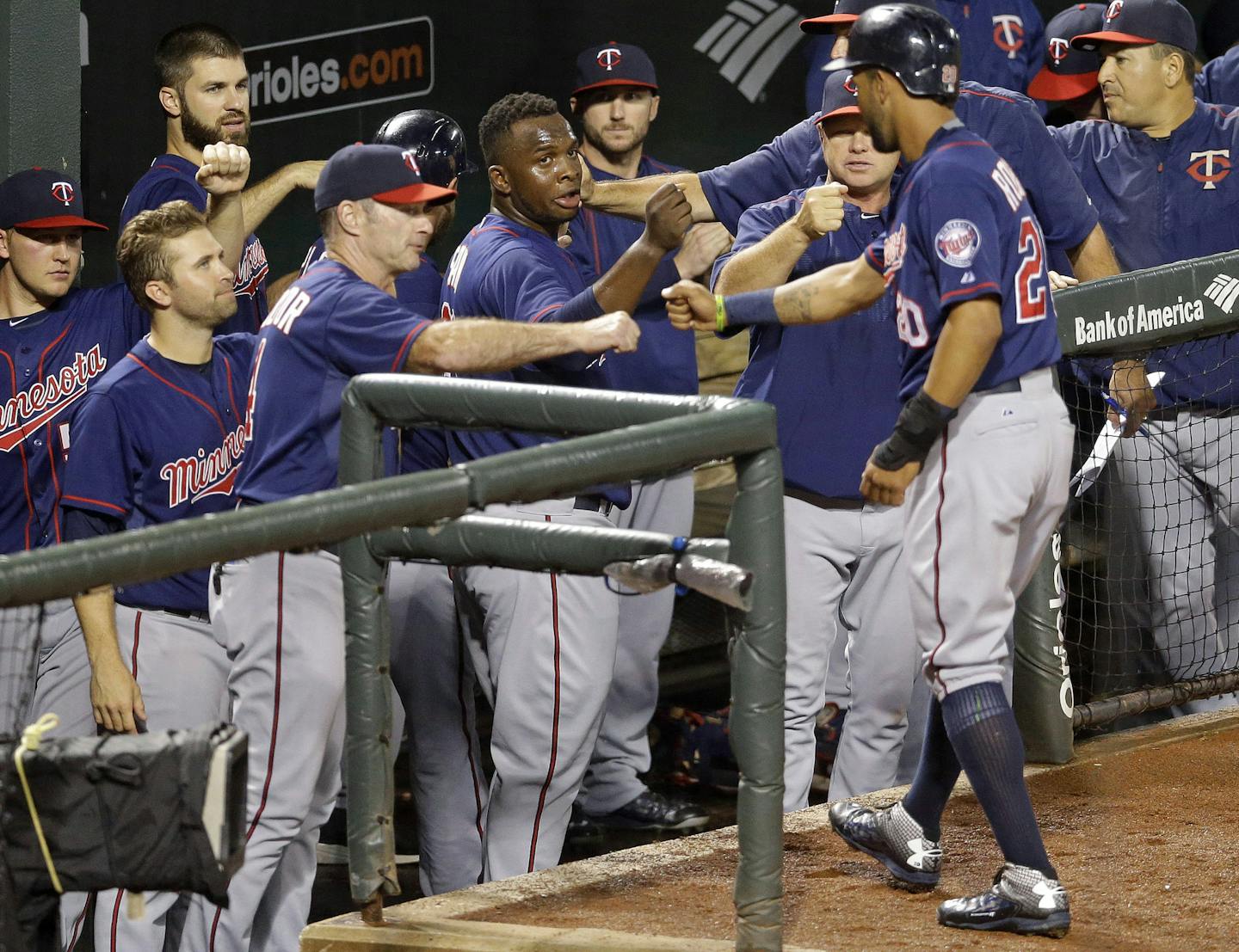 Teammates greet Minnesota Twins' Eddie Rosario, right, as he enters the dugout after scoring on a single by Kurt Suzuki.