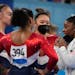Simone Biles, of the United States, talks to teammates Jordan Chiles, back to camera, Sunisa Lee and Grace Mc Callum, left, prior to the uneven bars c