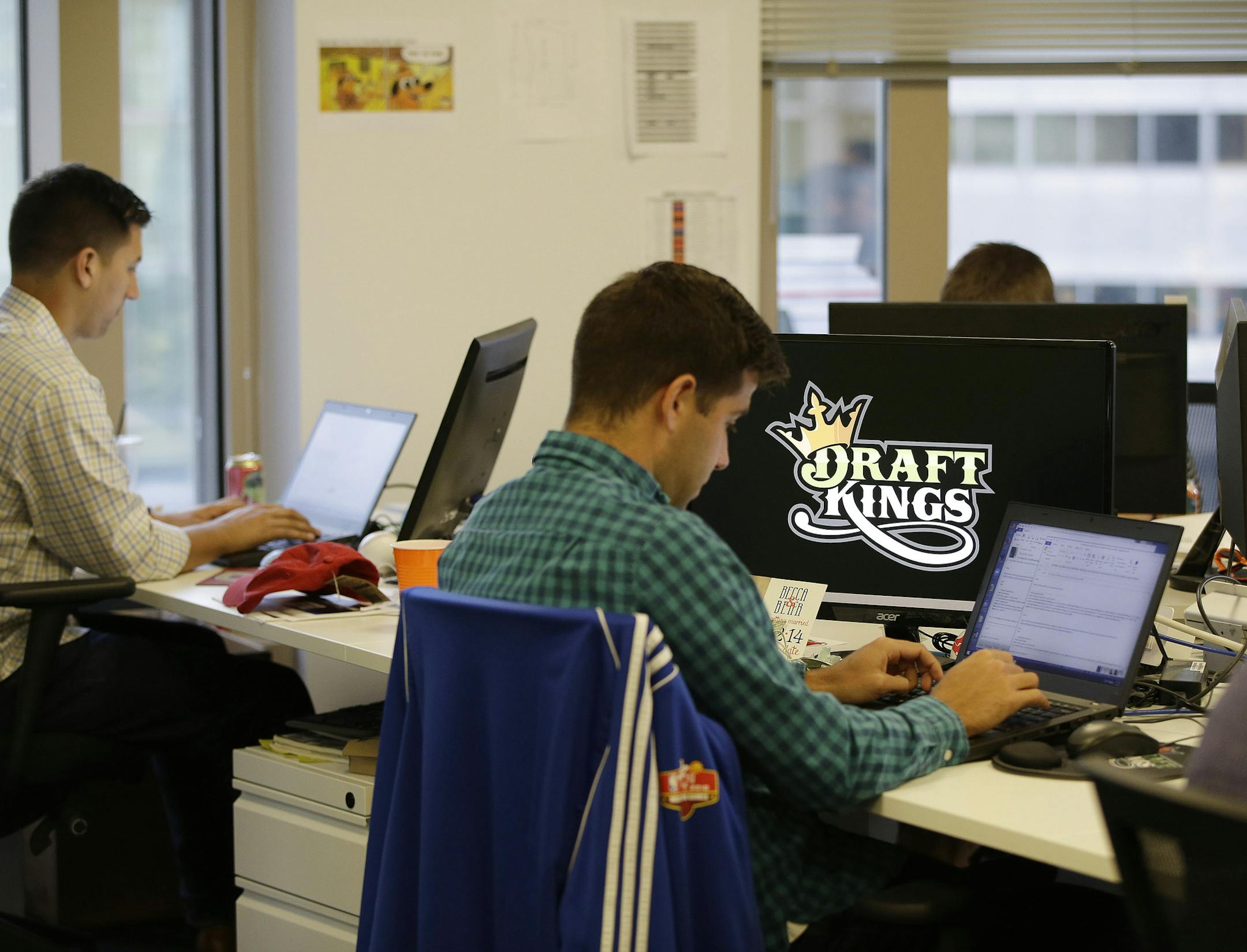 In this Wednesday, Sept. 9, 2015, photo, Bear Duker, a marketing manager for strategic partnerships at DraftKings, a daily fantasy sports company, works at his computer in Boston. The daily fantasy sports industry is eyeing a breakout season as NFL games begin. And its two dominant companies, DraftKings and FanDuel, are touting lucrative opening week prizes to try to draw more customers as more competitors pop up. (AP Photo/Stephan Savoia)