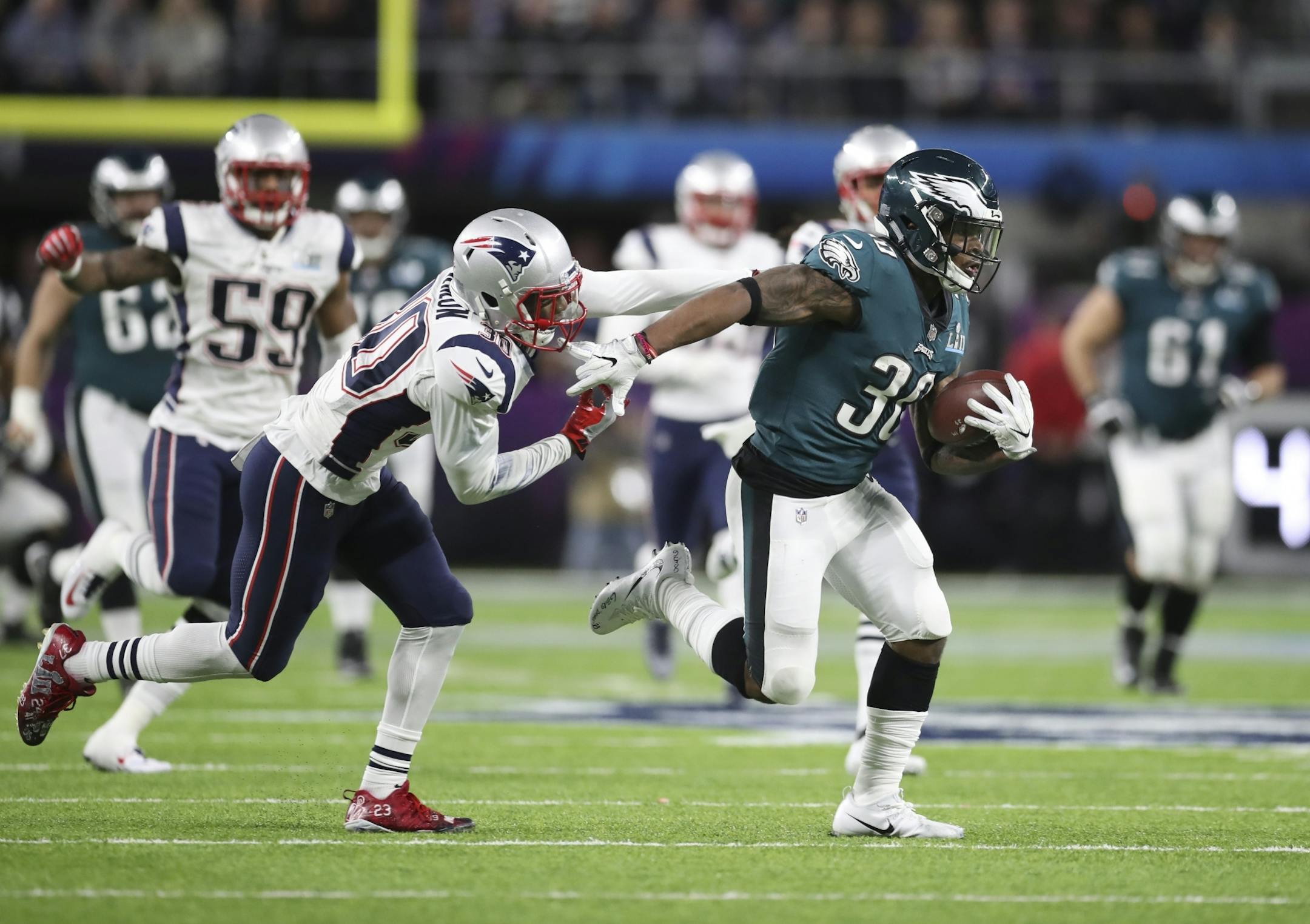 Philadelphia Eagles running back Corey Clement (30) tried to elude New England Patriots defensive back Duron Harmon (30) during Super Bowl LII.