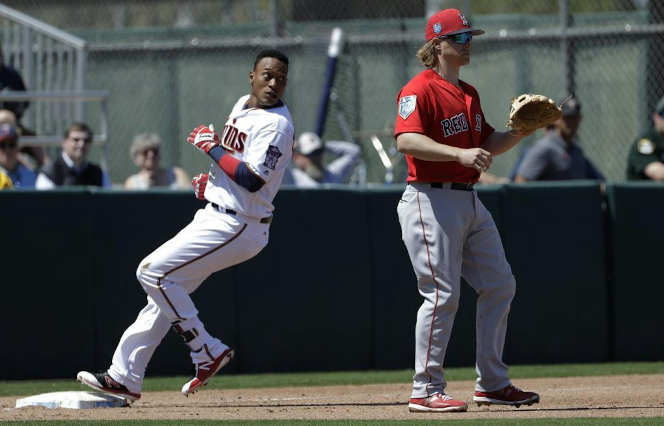 Minnesota Twins' Jorge Polanco, left, goes into third base ahead of the throw to Boston Red Sox's Brock Holt after hitting a triple off Red Sox pitcher Chris Sale during the fourth inning of a spring training baseball game Wednesday, March 14, 2018, in Fort Myers, Fla.