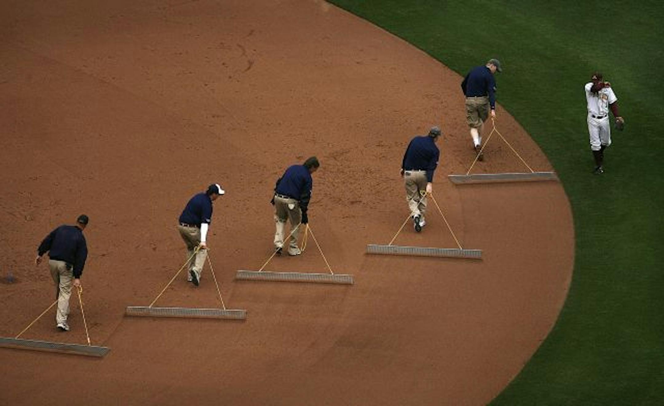 University of Minnesota second baseman AJ Pettersen walked to his position as groundskeepers teamed up to groom the infield at Target field during a game against Louisiana Tech.